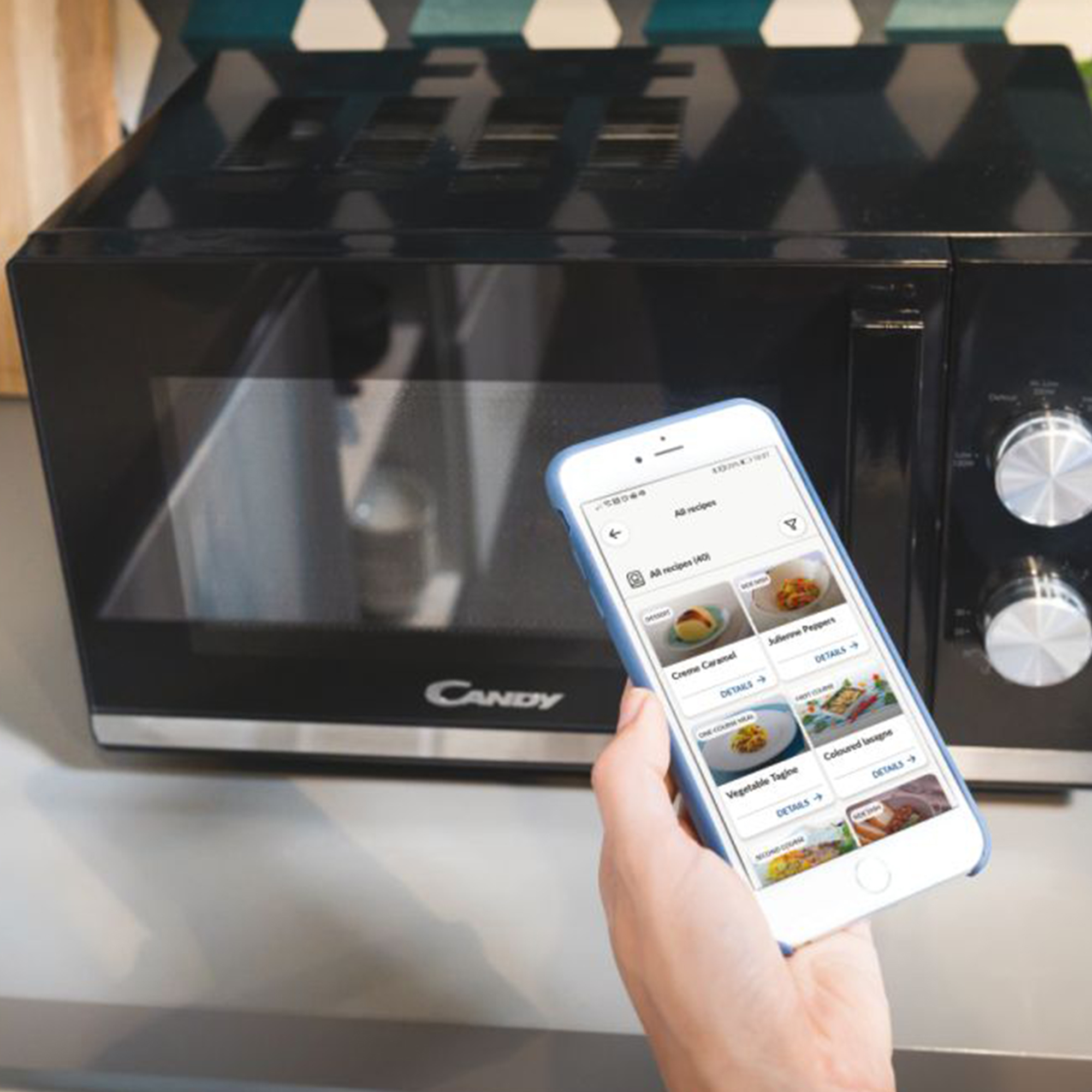 Een smartphone toont recepten naast een zwarte magnetron.