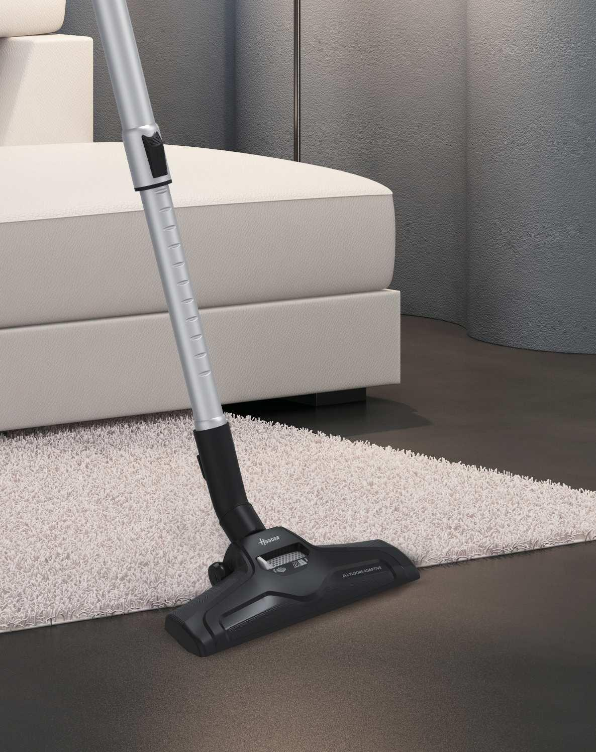 Ein Staubsaugerkopf auf einem weißen Teppich vor einem Sofa.