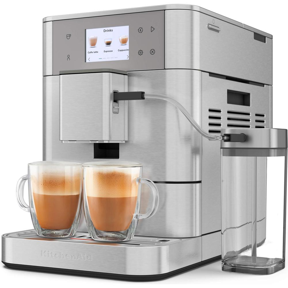 Eine silberne Kaffeemaschine mit zwei Tassen Kaffee und einem Milchbehälter.