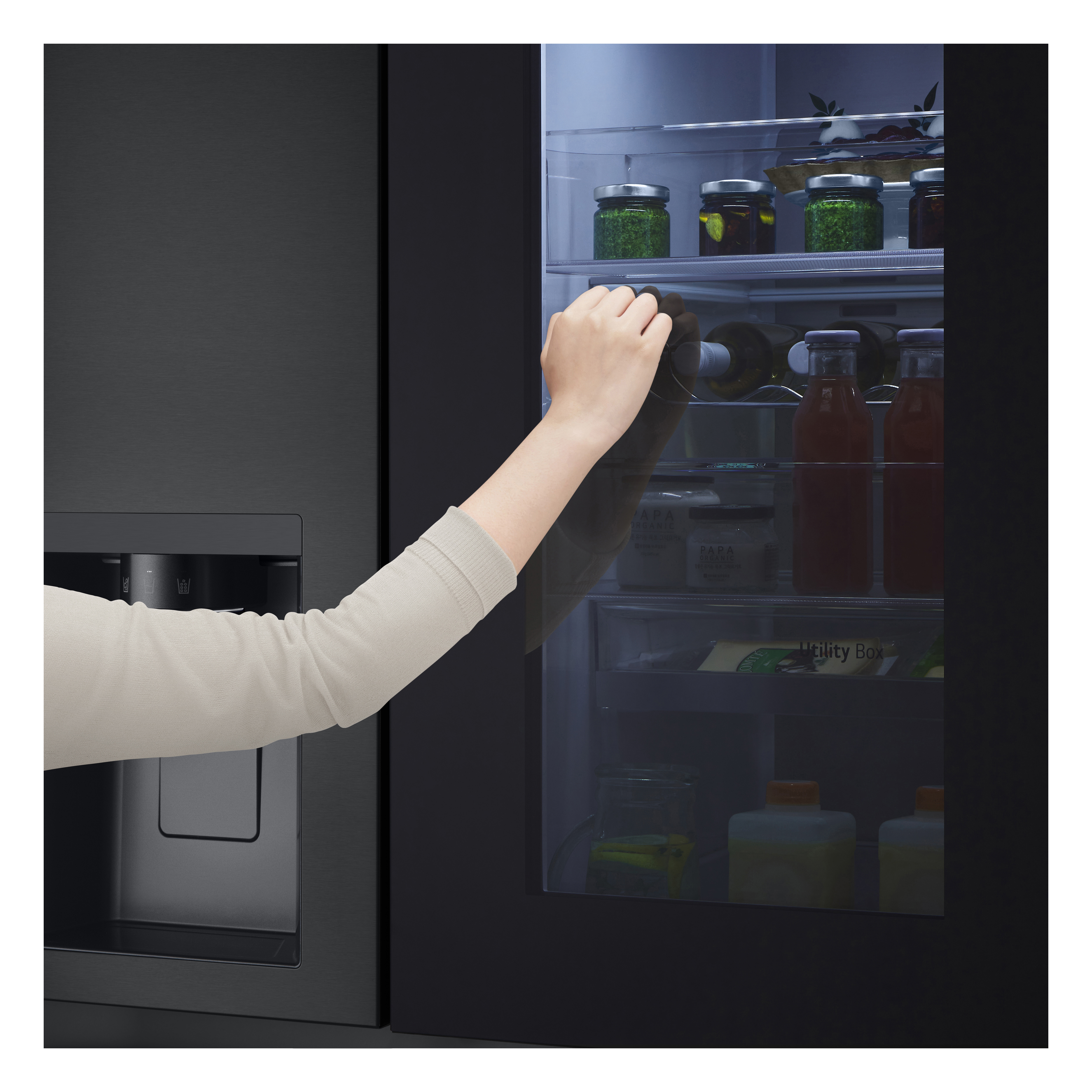 Eine Hand greift nach einer Flasche in einem dunklen Kühlschrank mit Glasfront.