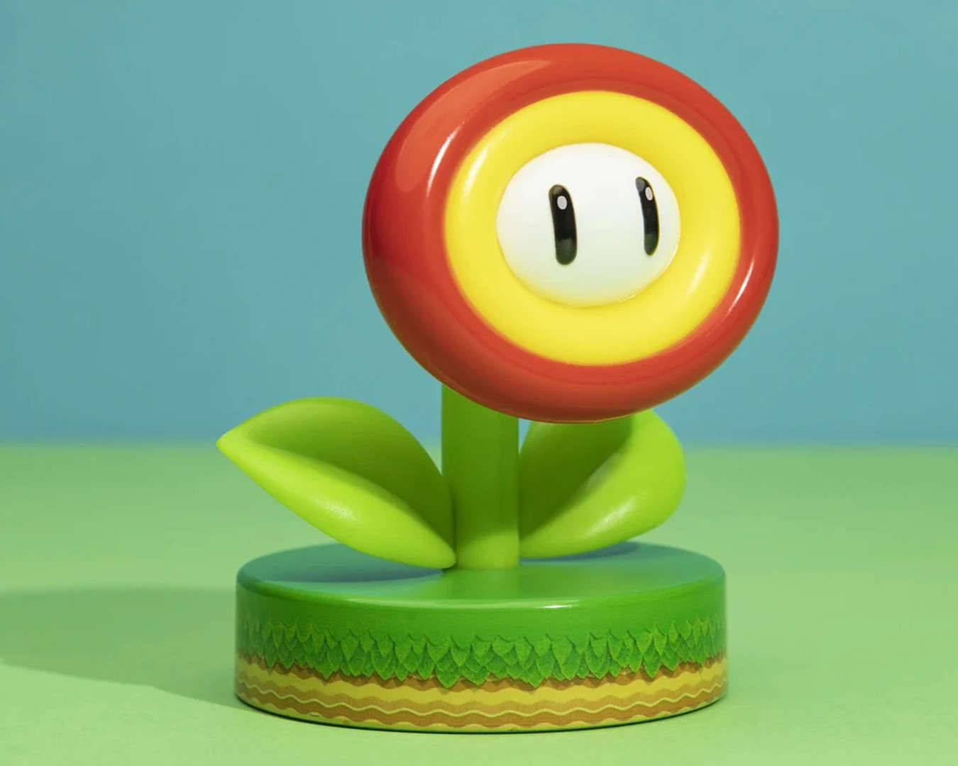 Figurka Piranha Plant na zielonej podstawie na niebieskim tle.