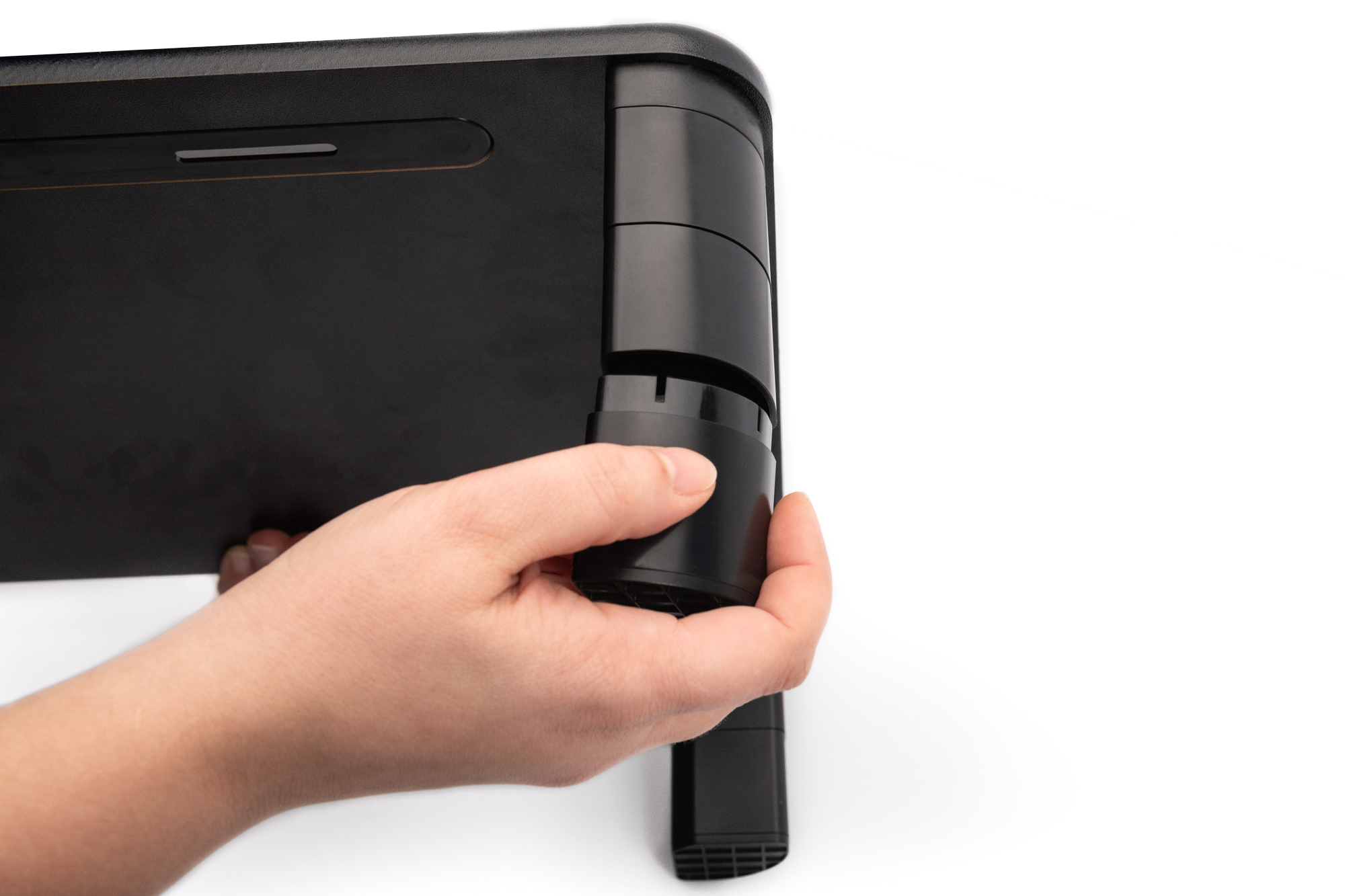 Eine Hand hält den ausziehbaren Ständer eines schwarzen Laptops, der auf einer weißen Fläche steht.