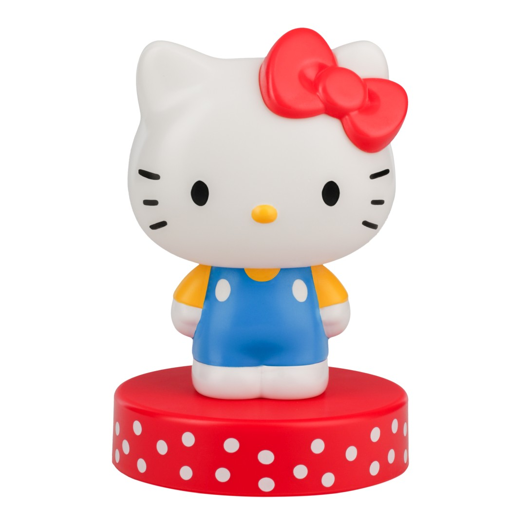Figurka Hello Kitty z czerwoną kokardką, niebieskimi ogrodniczkami, na czerwonej podstawie w białe kropki.