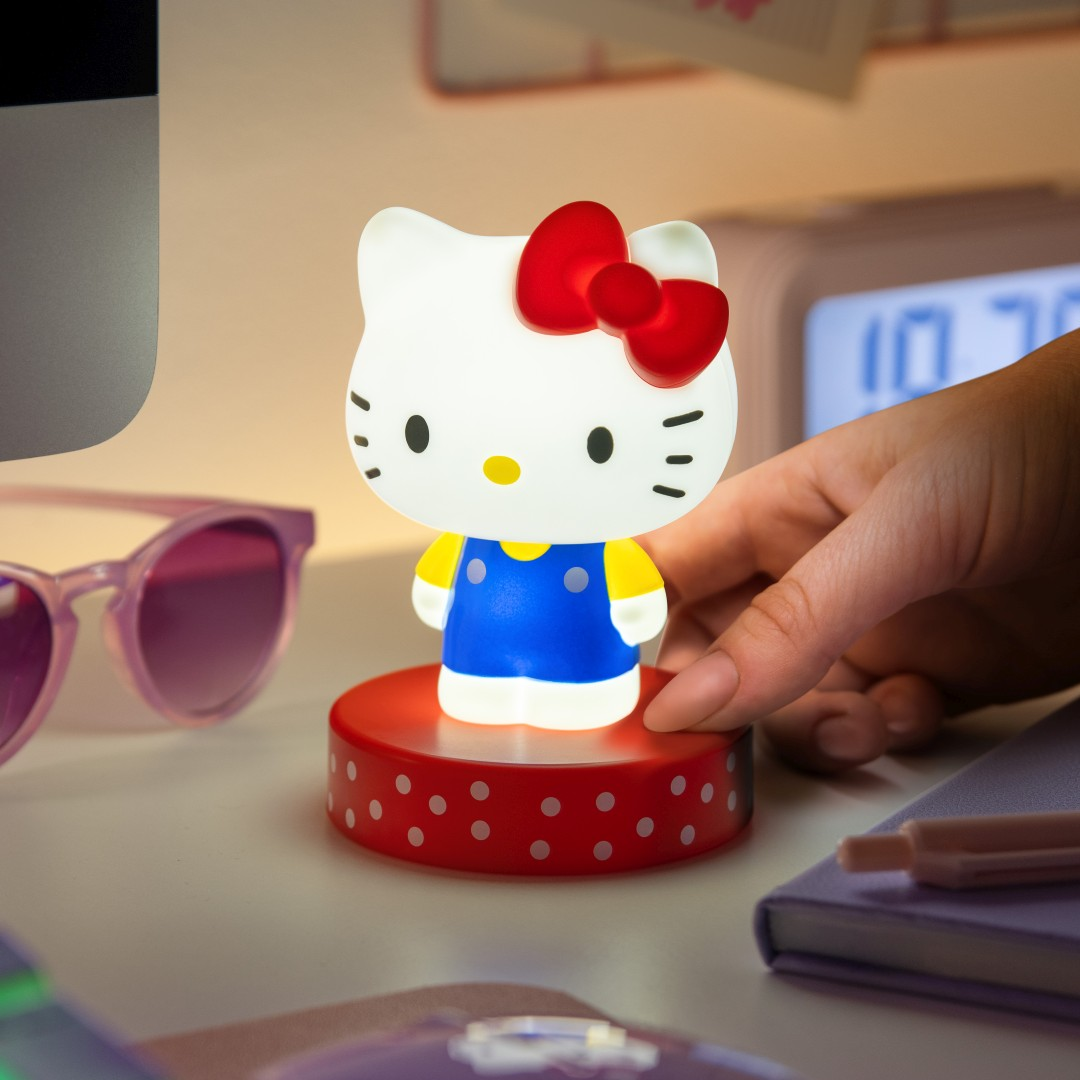 Świecąca figurka Hello Kitty na czerwonej podstawie w białe kropki.