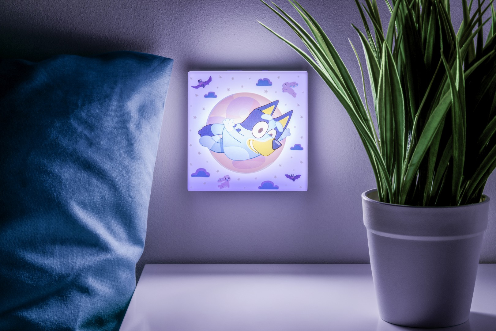 Lampka nocna Bluey z kreskówkowym psem na księżycu wisi na ścianie.