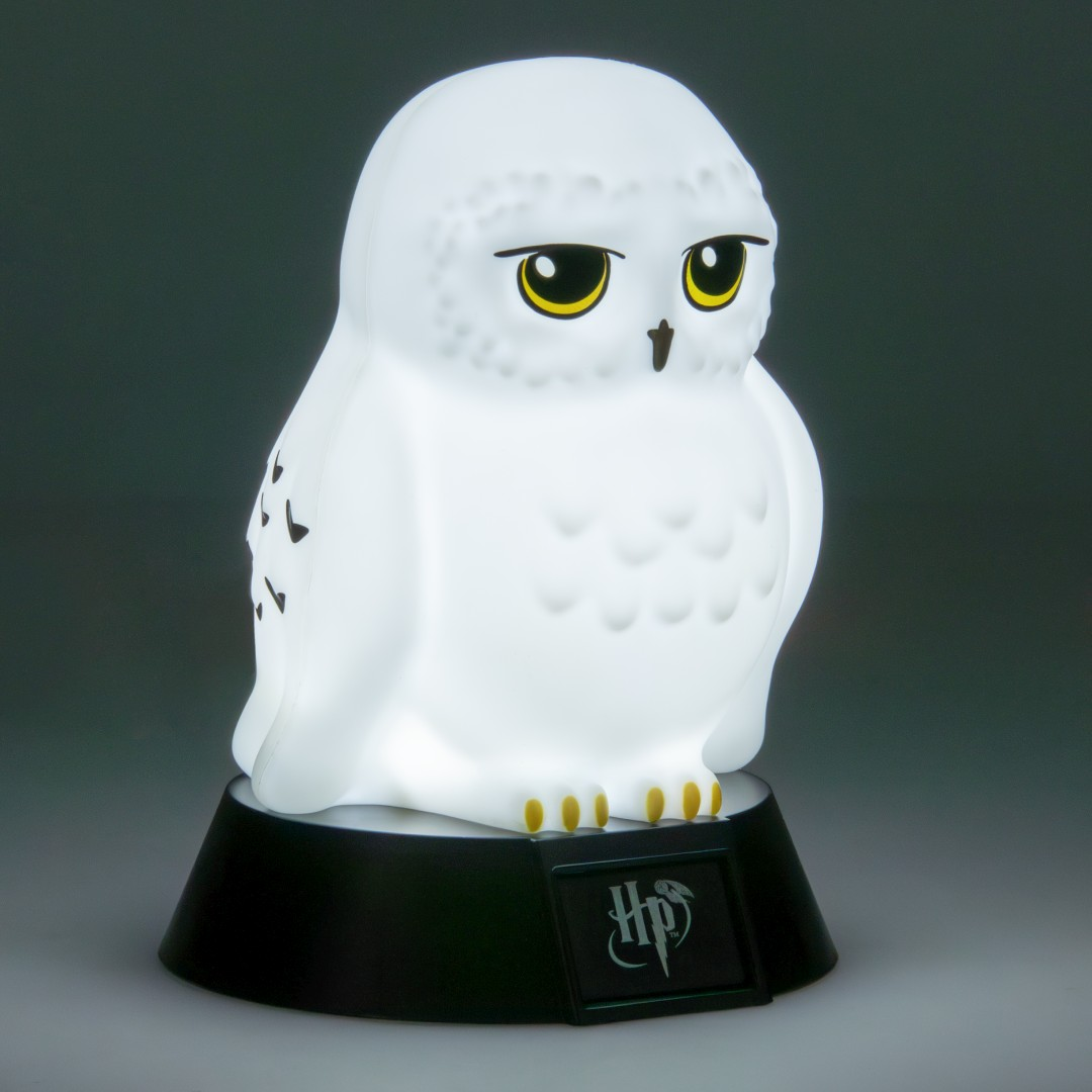 Biała lampa w kształcie sowy z żółtymi oczami stoi na czarnej podstawie z logo HP.