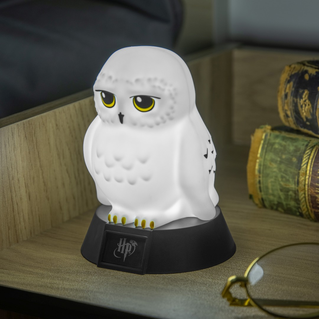 Biała lampa sowa z logo Harry'ego Pottera na podstawie.