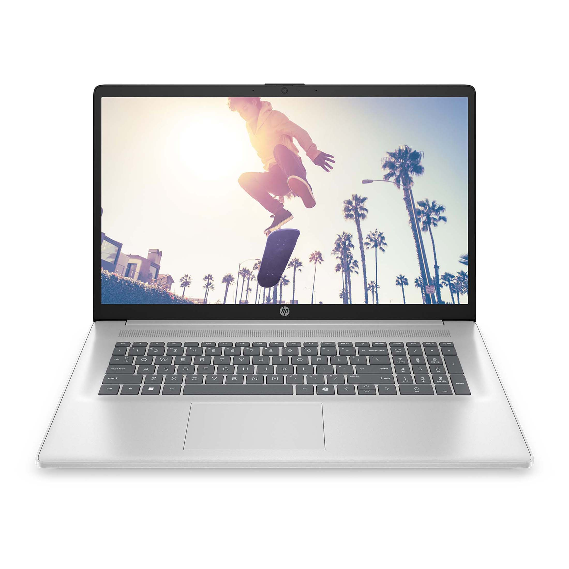 Un laptop argentato mostra uno skater che salta sopra palme sullo schermo.