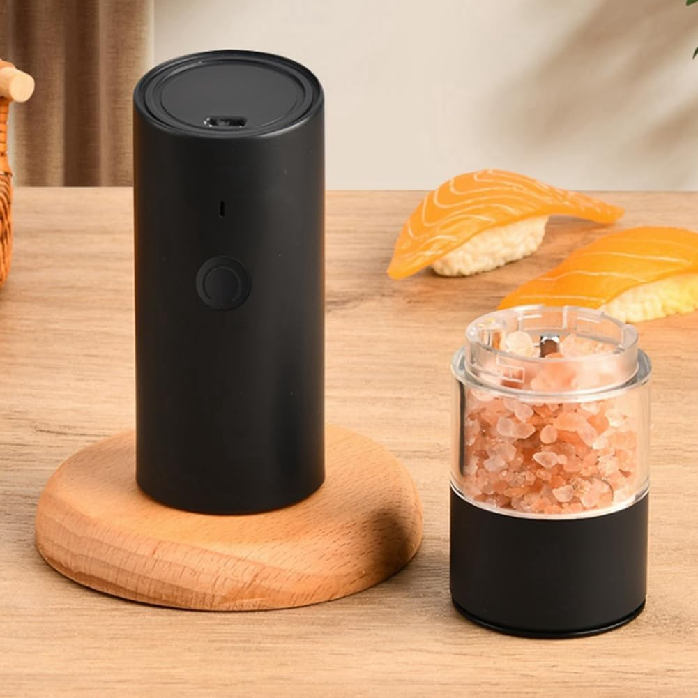 Schwarzer elektrischer Grinder neben einer Salzmühle mit rosa Kristallen, Sushi im Hintergrund.