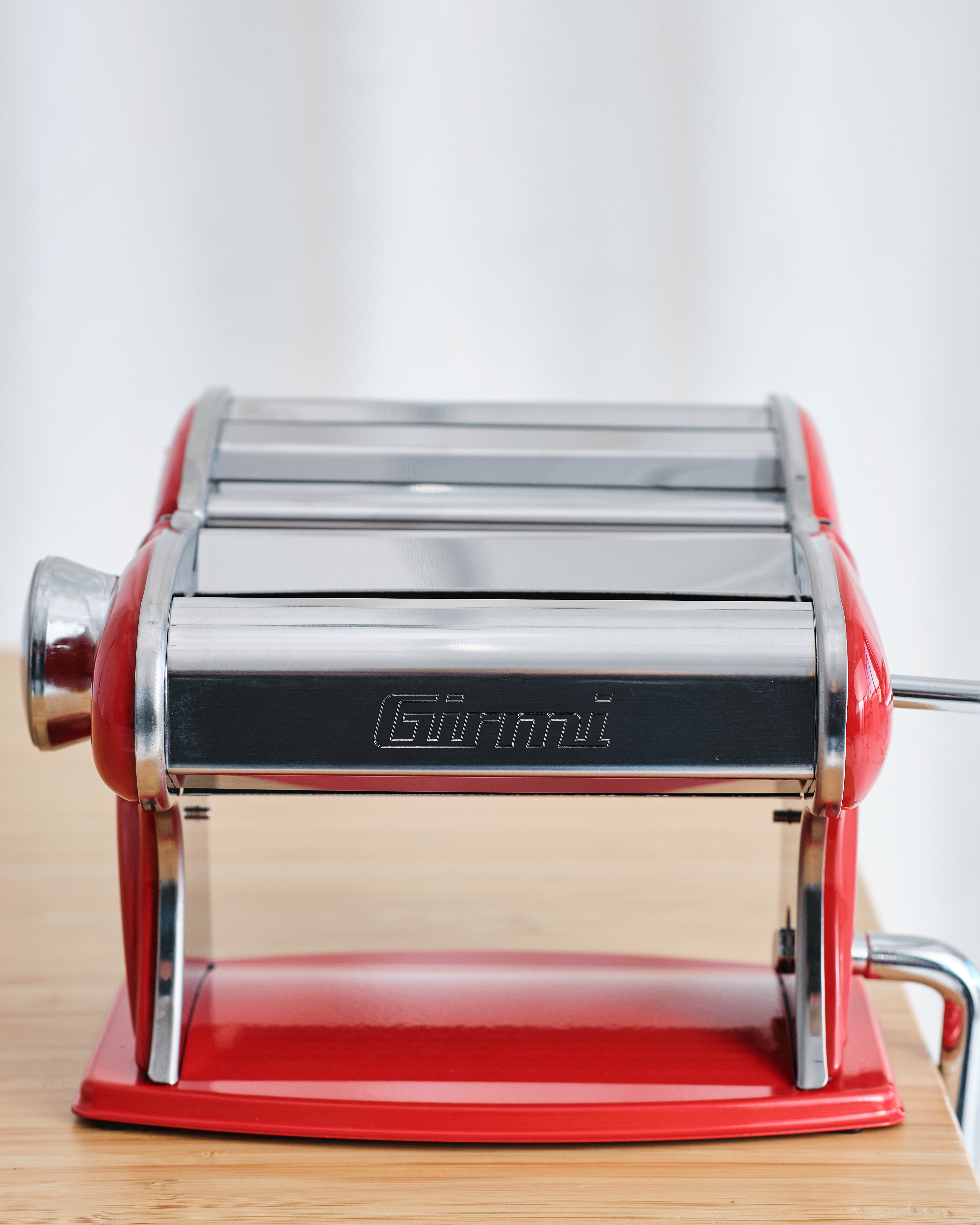 Eine rote Girmi Nudelmaschine aus Metall steht auf einem Holztisch.