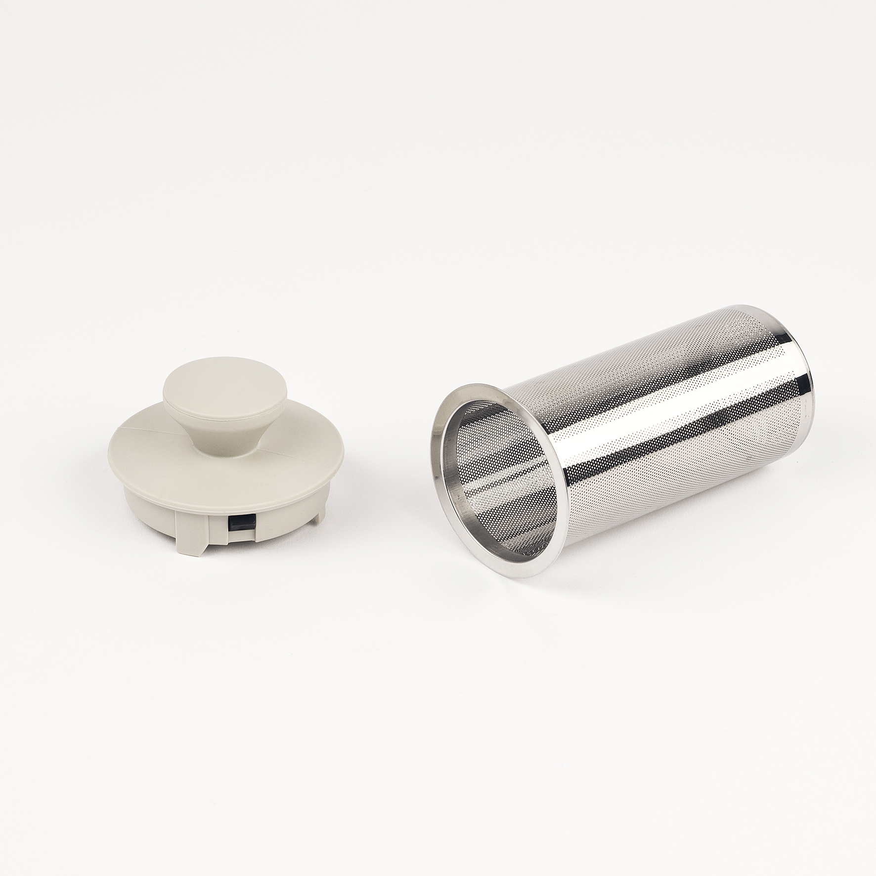 Ein grauer Teekannenverschluss und ein zylindrisches Teesieb aus Metall.