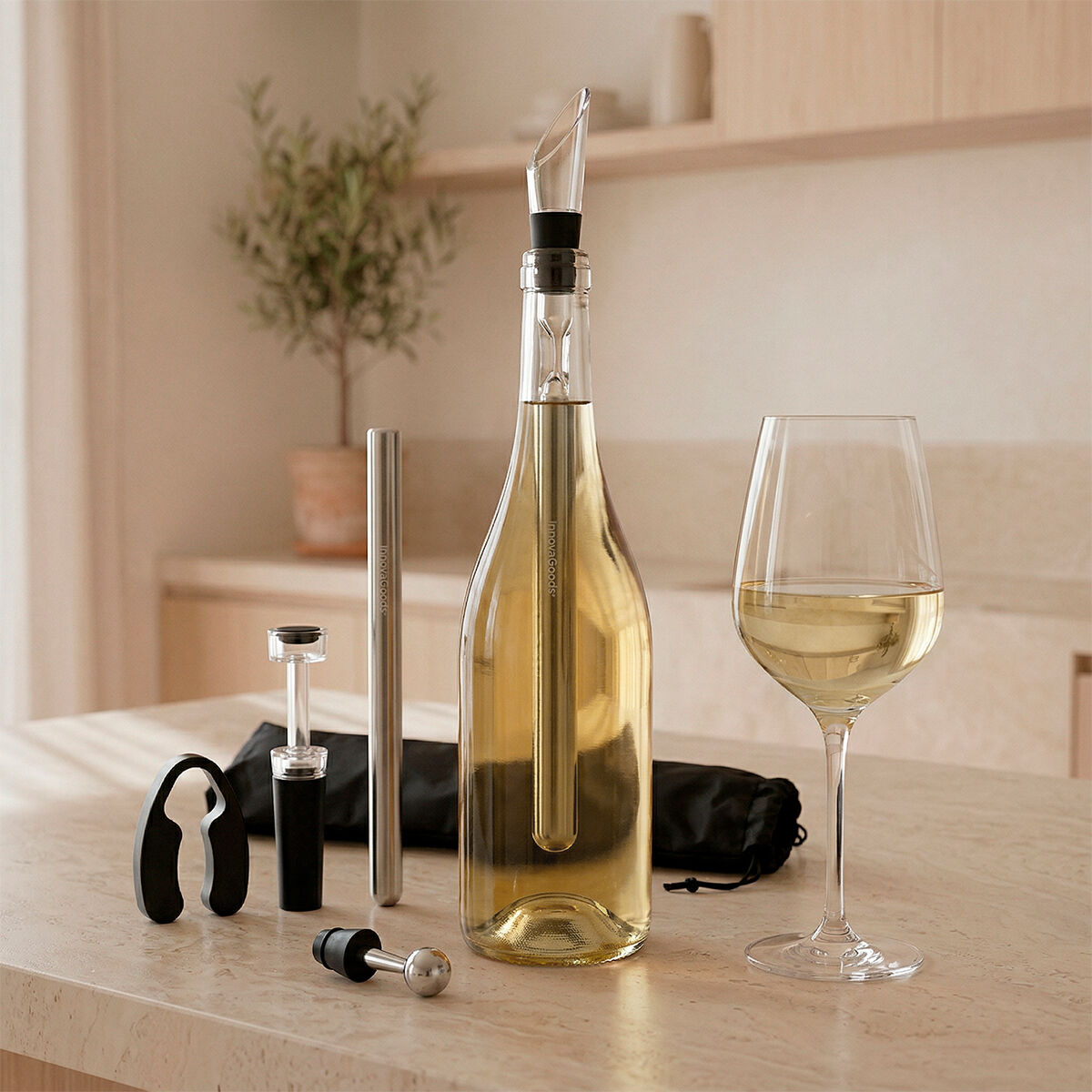 Ein Weinkühlerstab in einer goldenen Flasche Weißwein, daneben ein Glas, ein Korkenzieher und ein Stopfen.