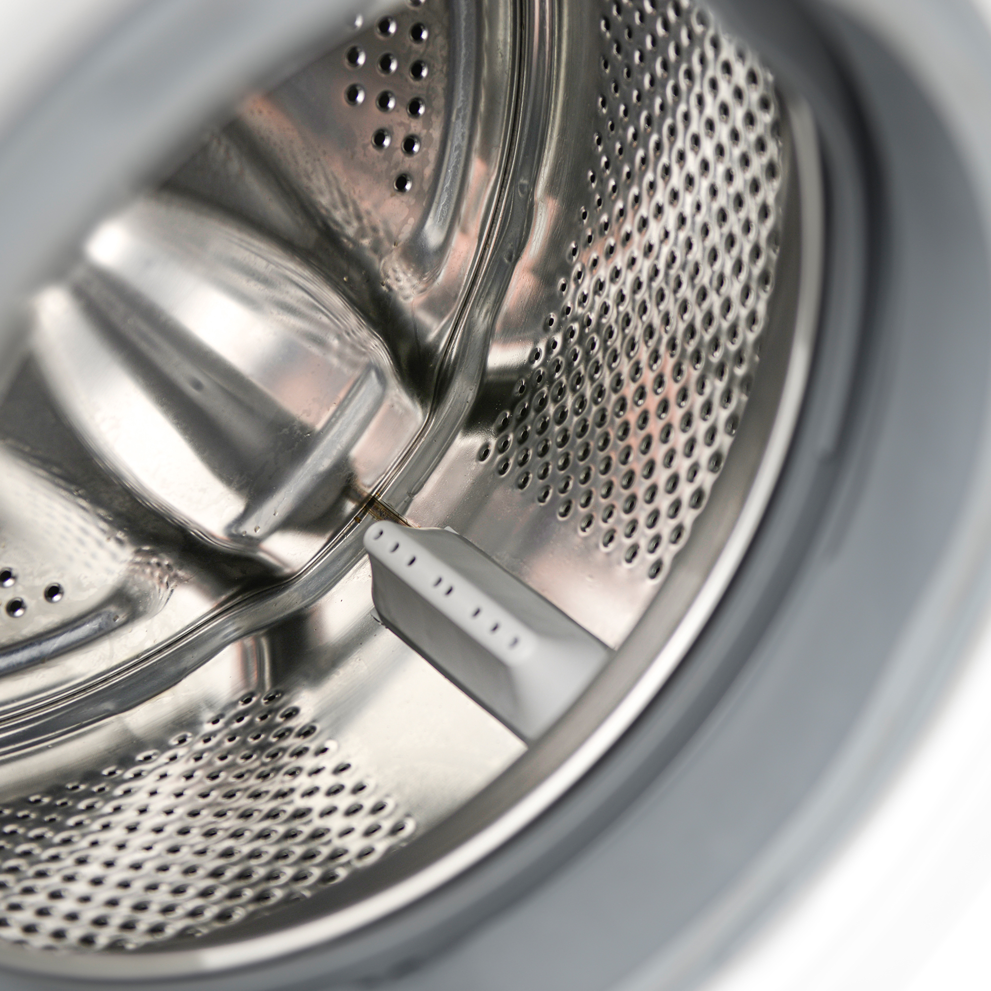 Detailansicht der Trommel einer Waschmaschine mit Metalloberfläche und Perforation.