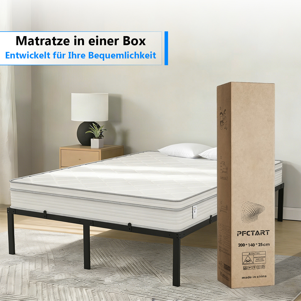 Eine Matratze auf einem Metallbettgestell neben einer Pappschachtel.
