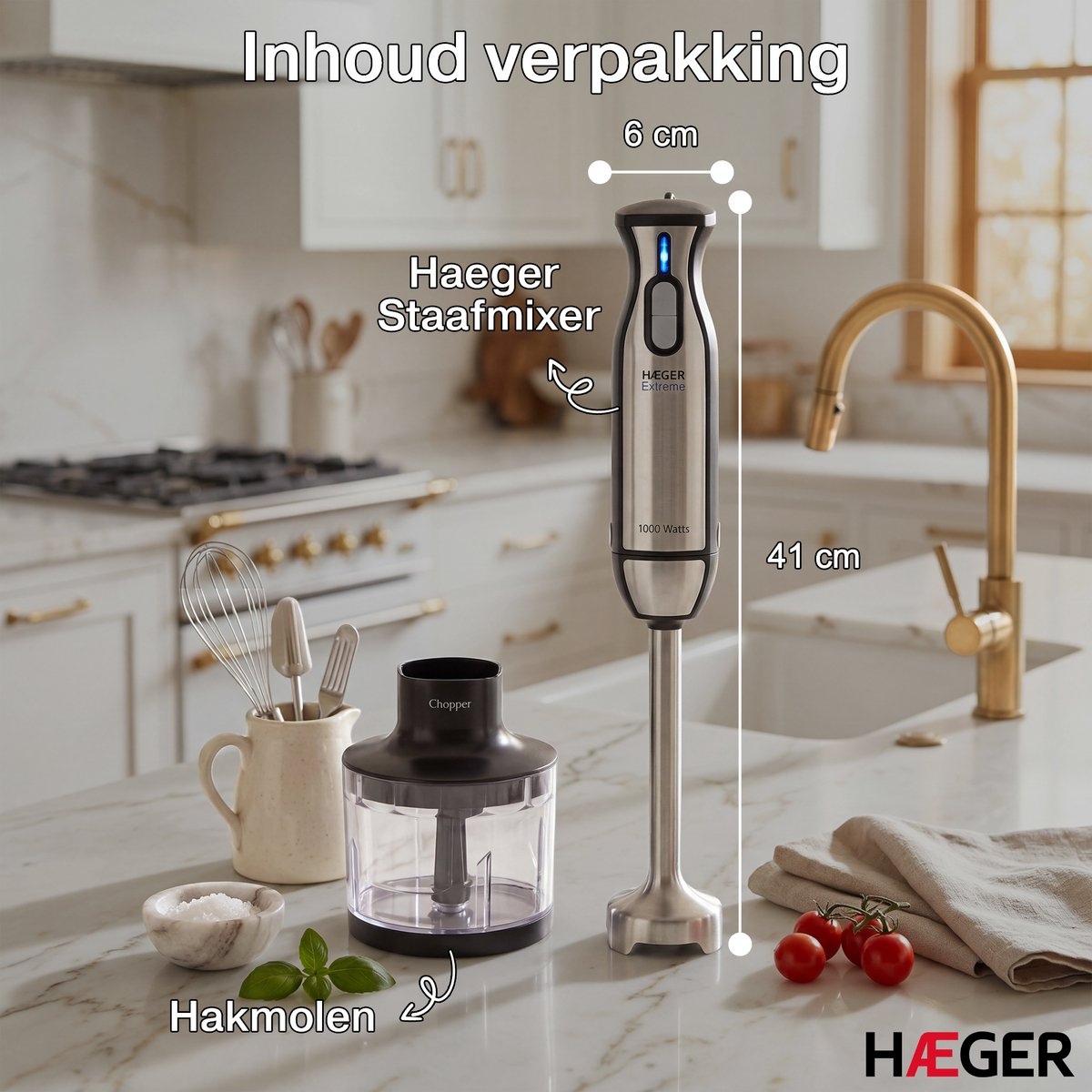 Zilveren staafmixer met hakmolen-opzetstuk, maatbeker en tomaten op een marmeren aanrechtblad.