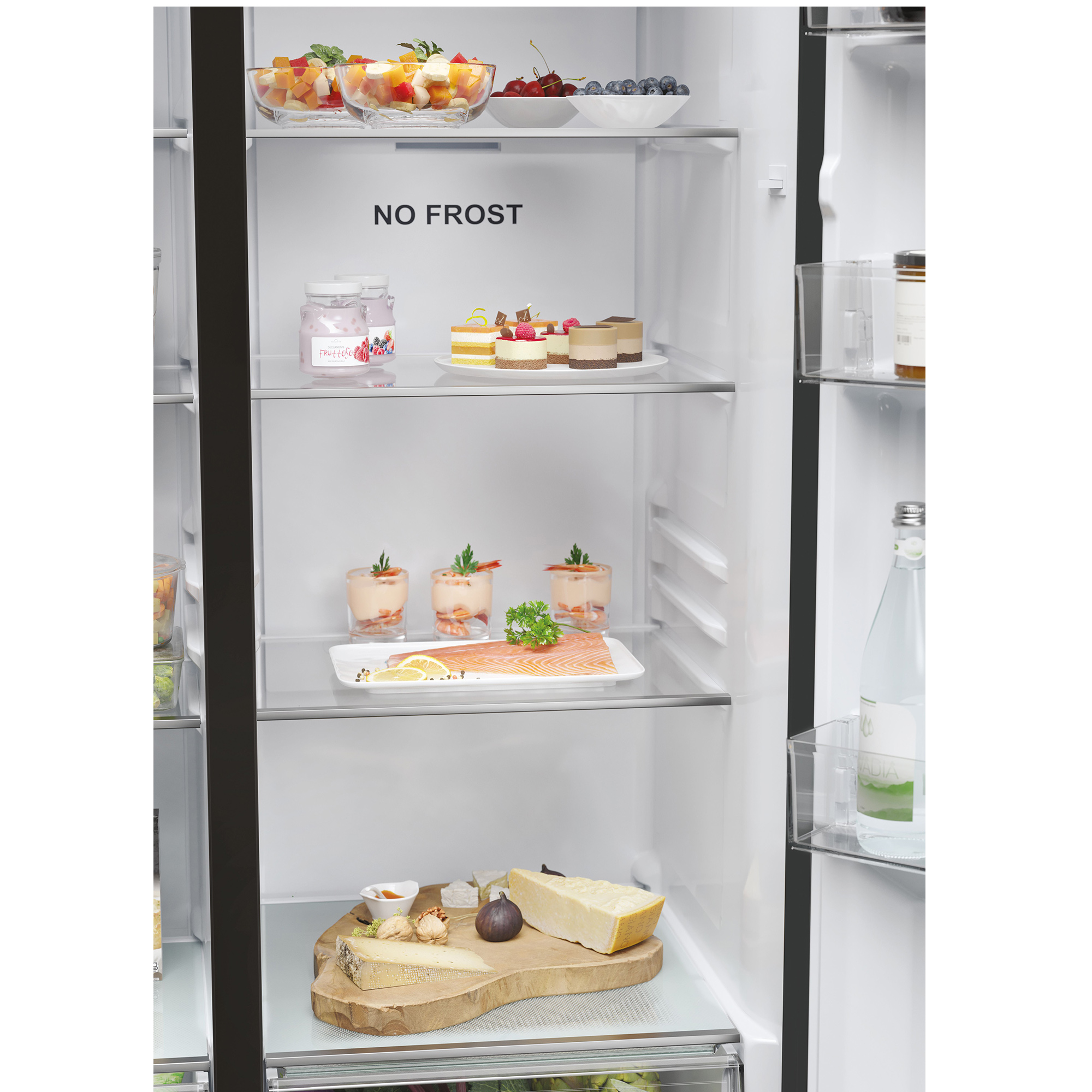 Frigorifero con frutta, torte, salmone, formaggio e bevande sugli scaffali.