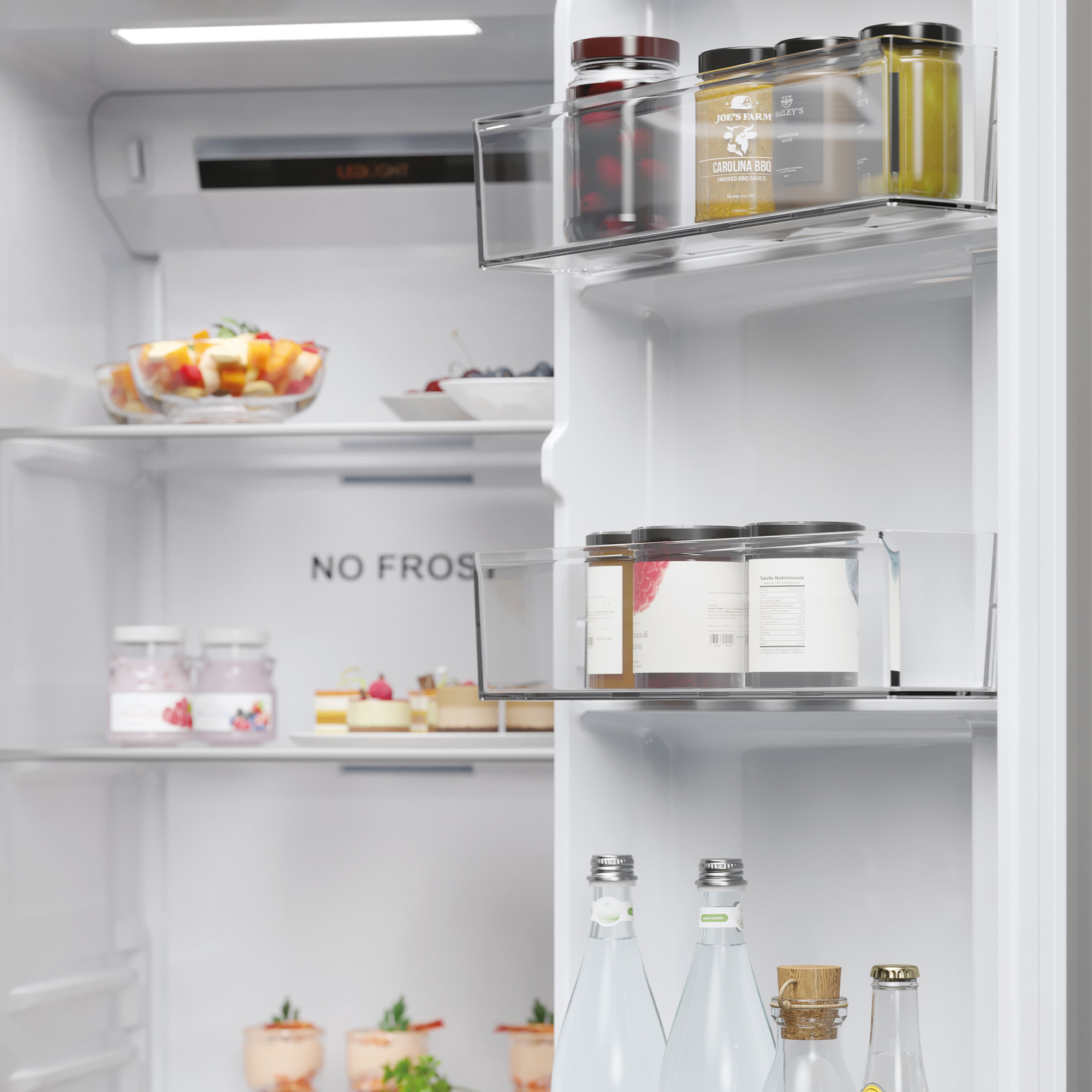 Interior de refrigerador con frutas, pasteles, salsas y botellas de agua.