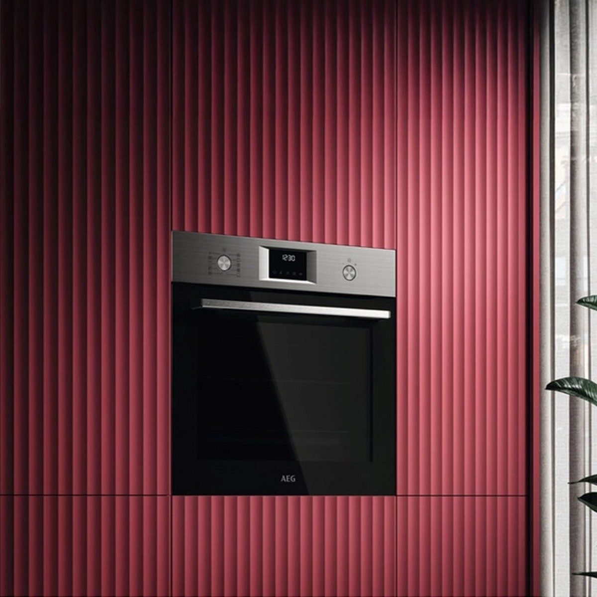 Horno empotrado moderno en un mueble rojo con ranuras verticales. Ventana al lado.