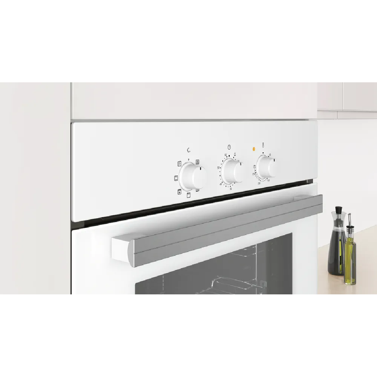 Horno empotrado blanco con tirador plateado y tres mandos, primer plano.