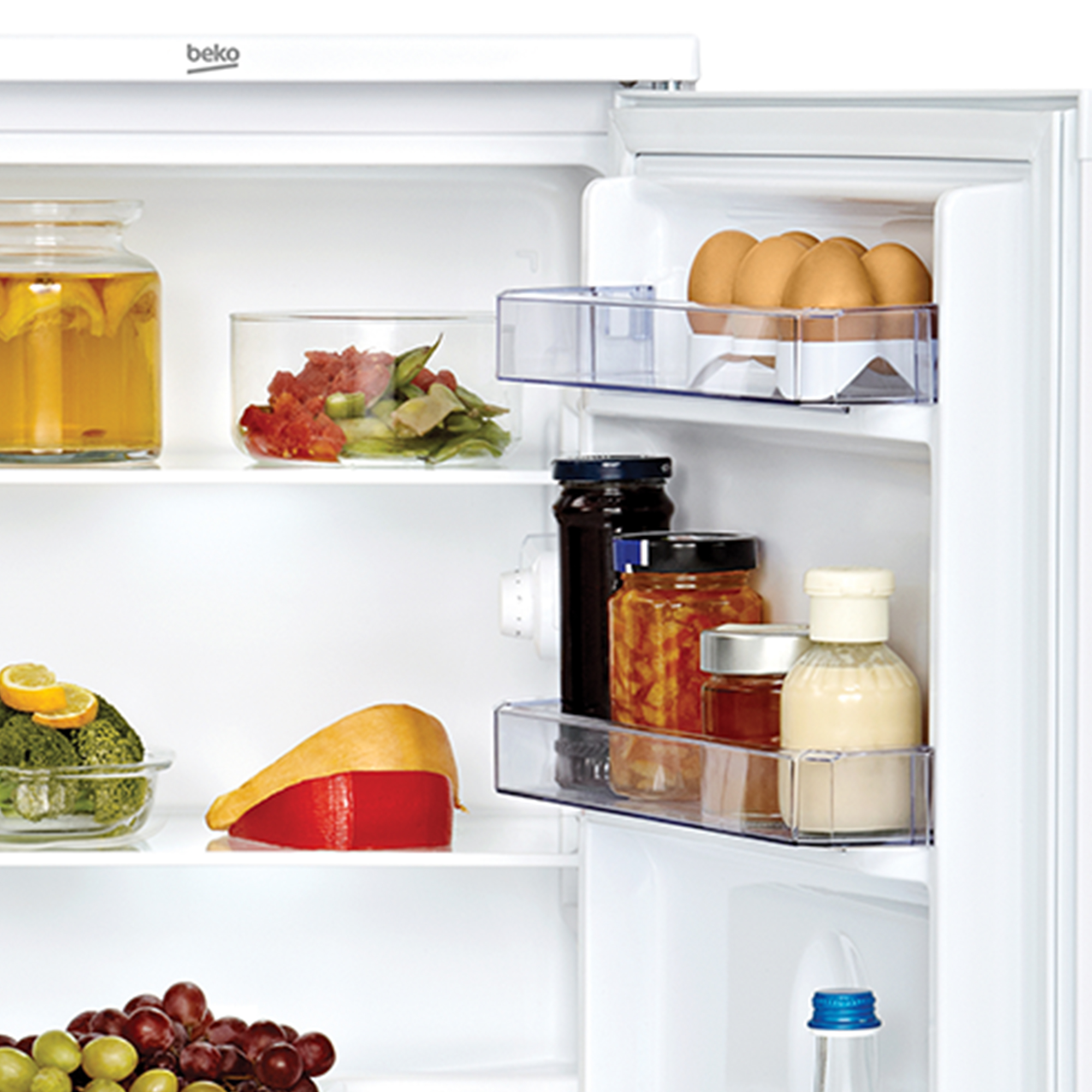 Interno di frigorifero con uova, barattoli di conserve e frutta.