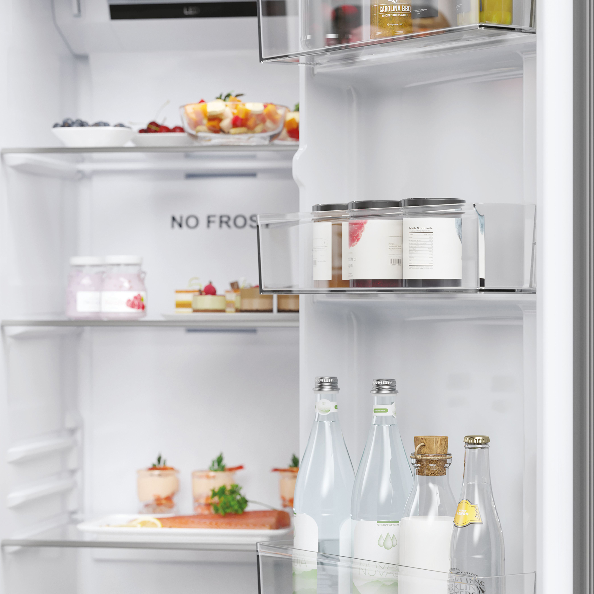 Ein Kühlschrank mit Lebensmitteln, darunter Obst, Kuchen, Saucen und Wasserflaschen.