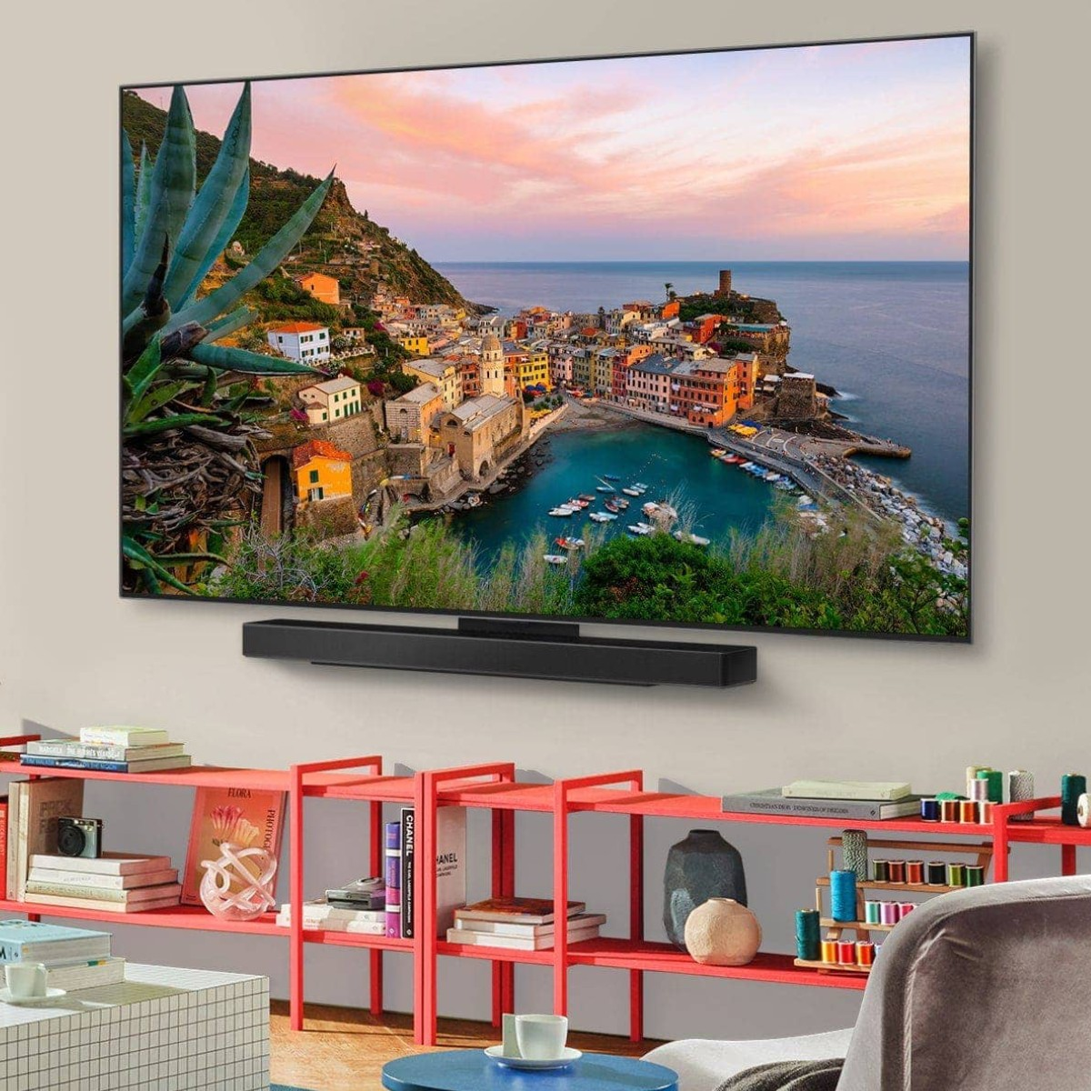 Platte tv toont schilderachtig kuststadje met kleurrijke huizen aan het water. Eronder een soundbar.