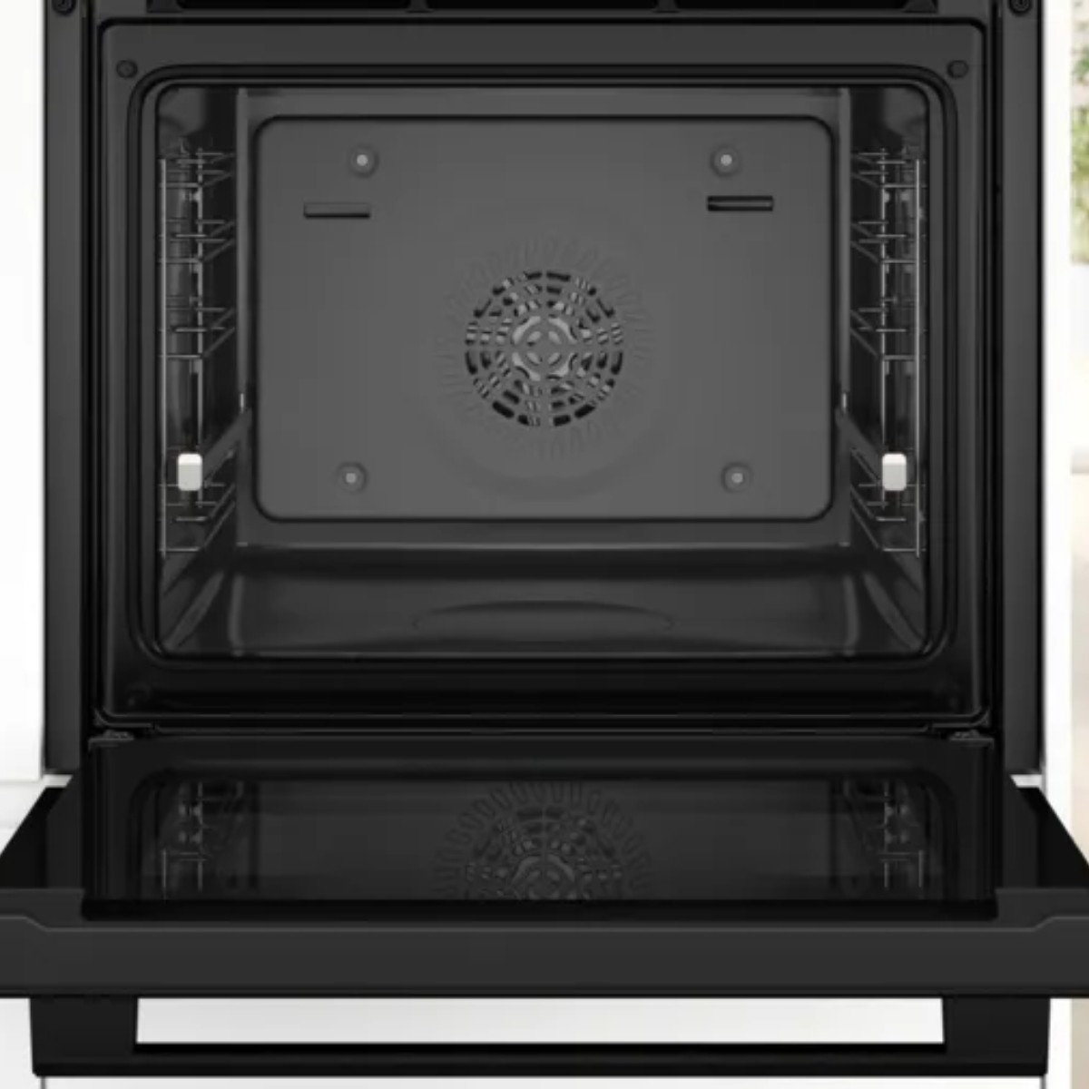 Interior de horno negro abierto con rejillas y cubierta de ventilador. Puerta inferior abierta.