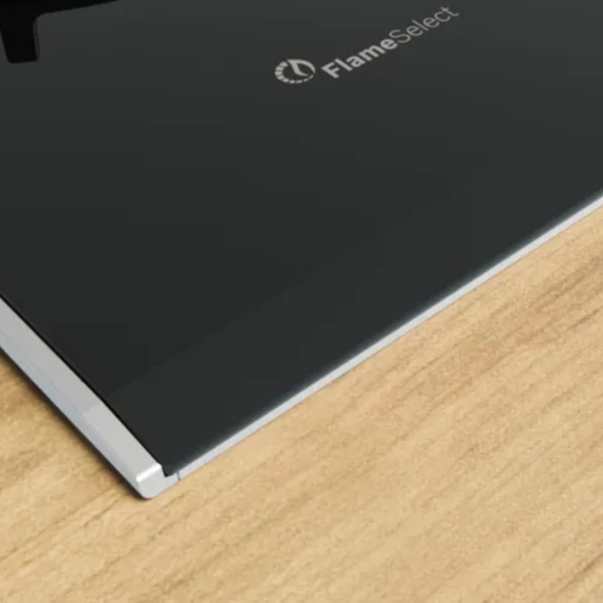 Czarna płyta grzewcza z srebrną ramką na drewnianej powierzchni. Logo "FlameSelect".