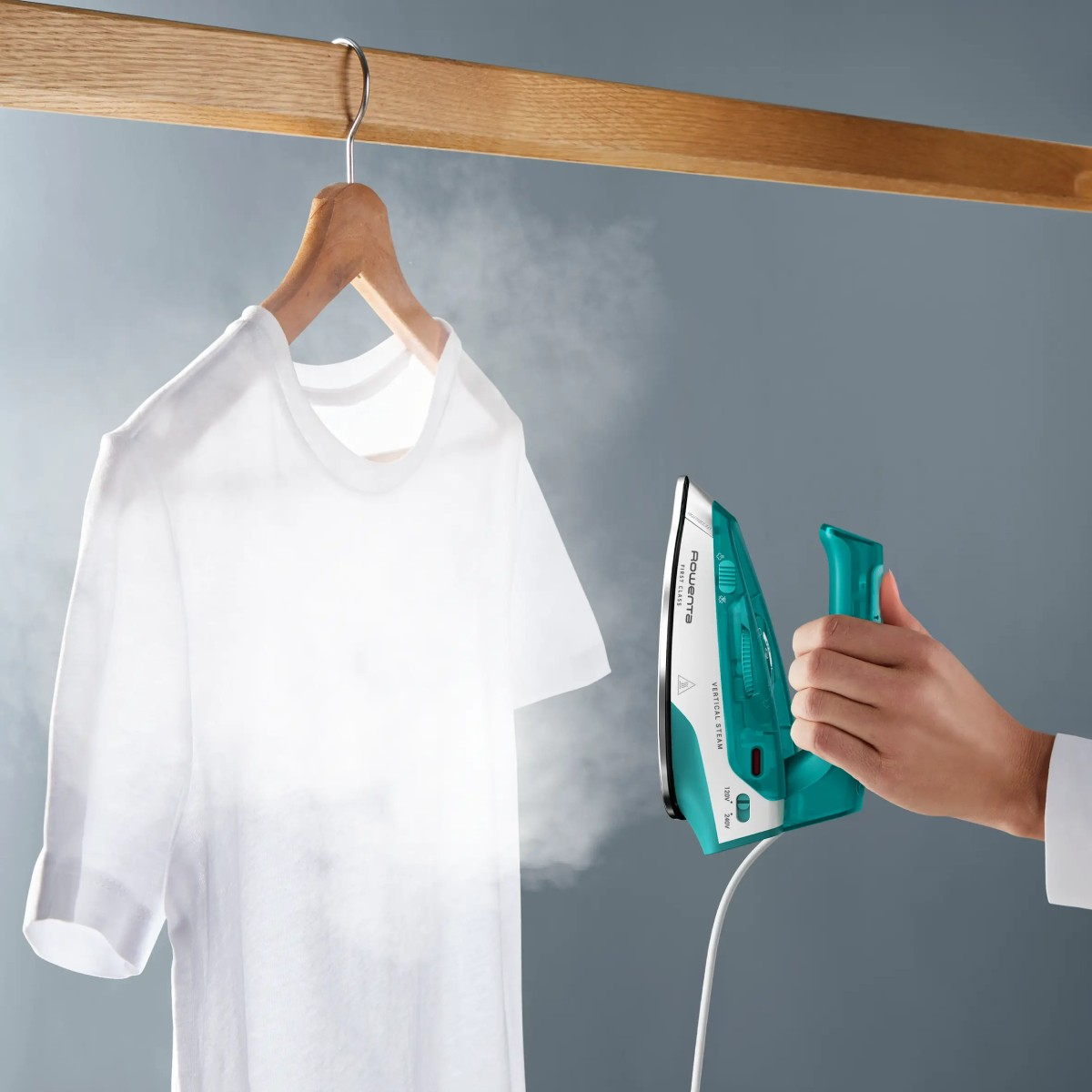 Una t-shirt bianca viene vaporizzata su un appendiabiti.