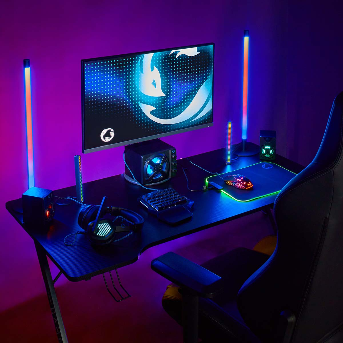 Ein Schreibtisch für Gamer mit Monitor, Tastatur, Maus, Kopfhörern und RGB-Beleuchtung.