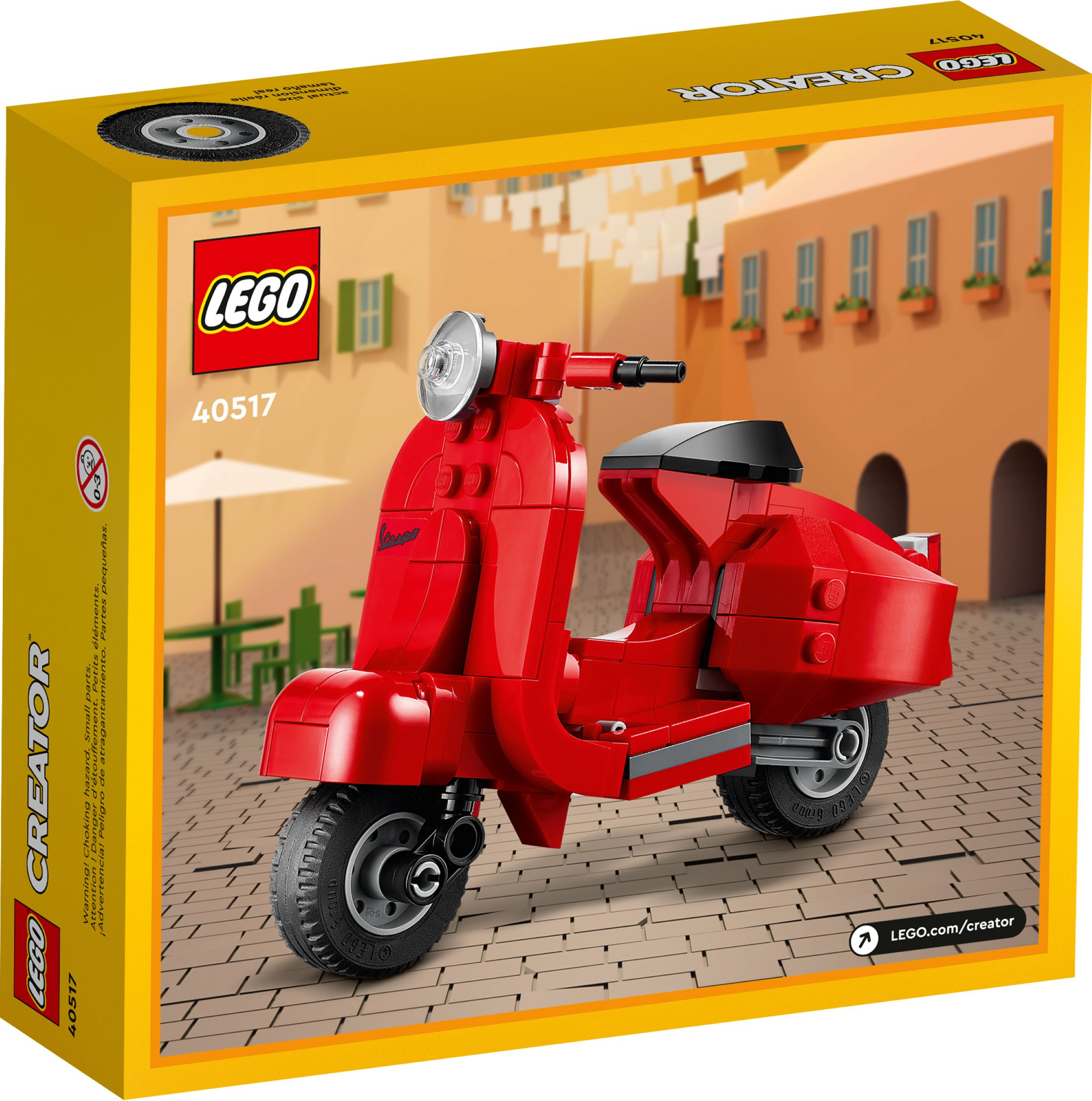 Scooter Vespa rossa LEGO Creator di fronte a un edificio con finestre e tavoli.