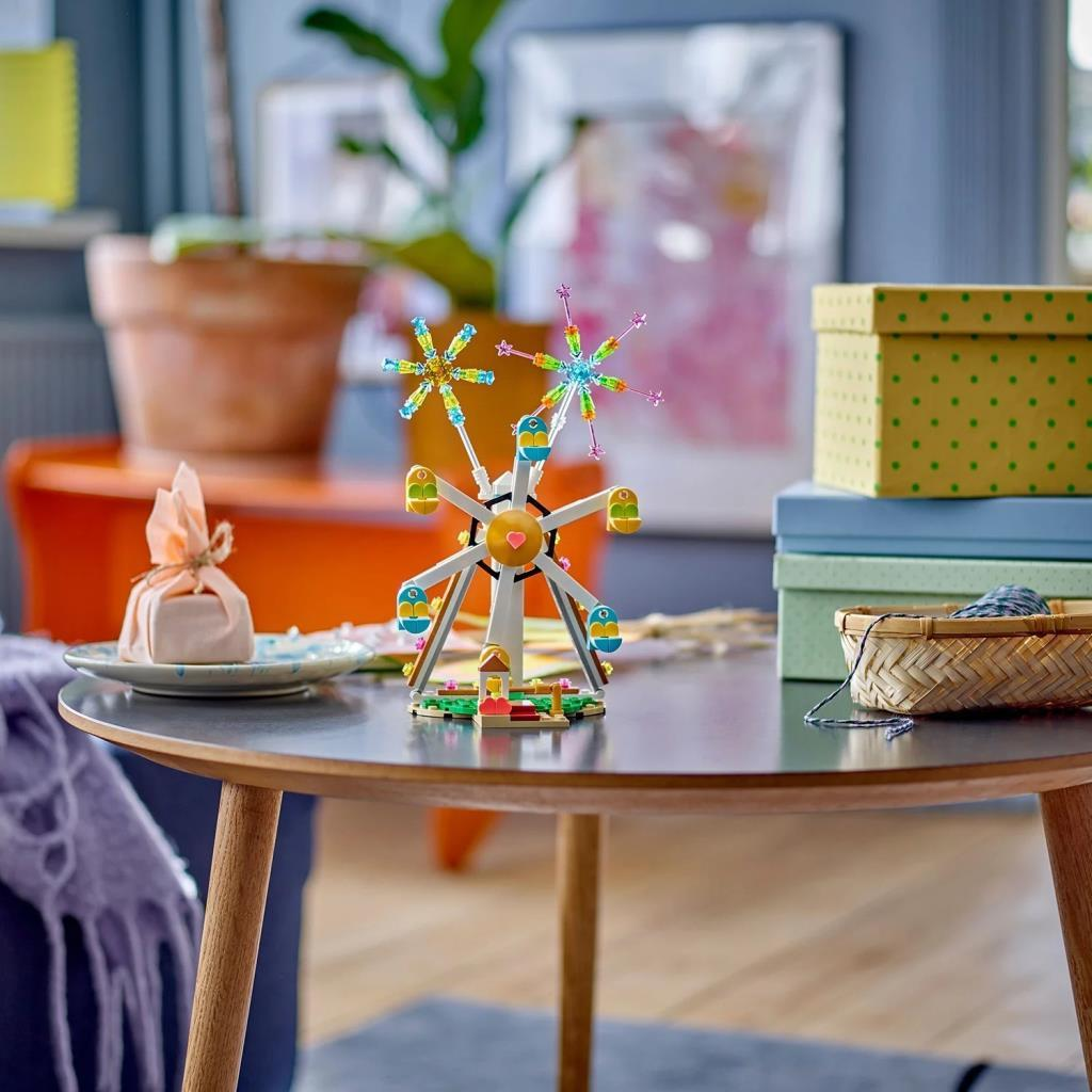 Un colorato modello di ruota panoramica Lego con due topper scintillanti su un tavolo.