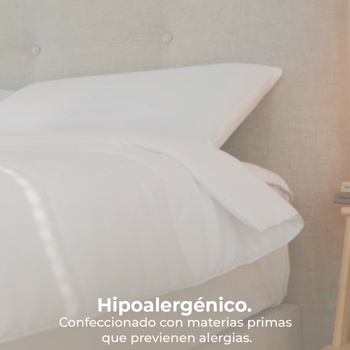 Un letto bianco con cuscino e piumone davanti a una testiera trapuntata.