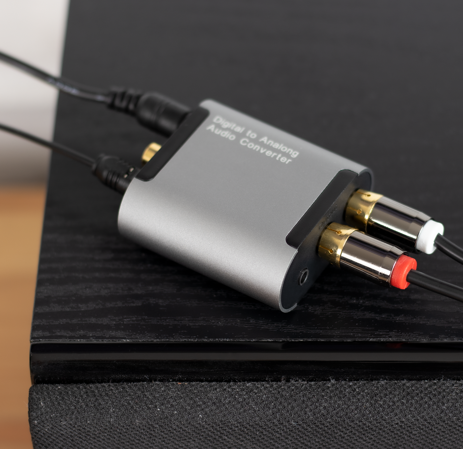 Una caja convertidora de audio plateada con cables conectados a puertos RCA.