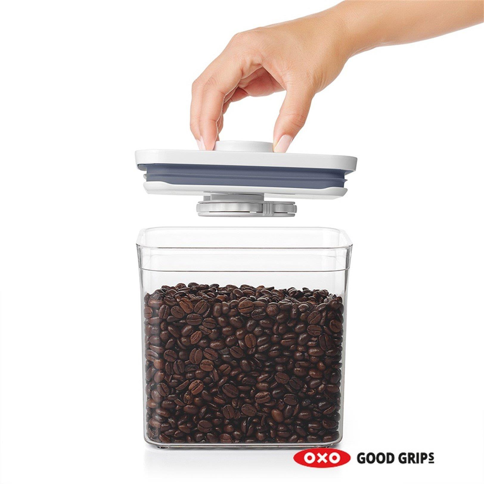 Una mano apre un contenitore ermetico pieno di caffè.