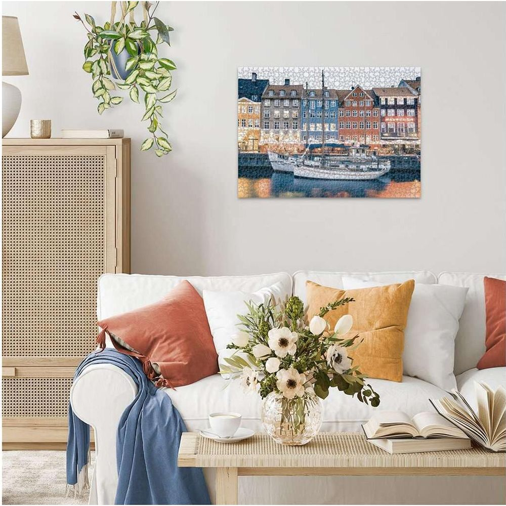 Un salon avec un canapé et un tableau de bâtiments et bateaux colorés.