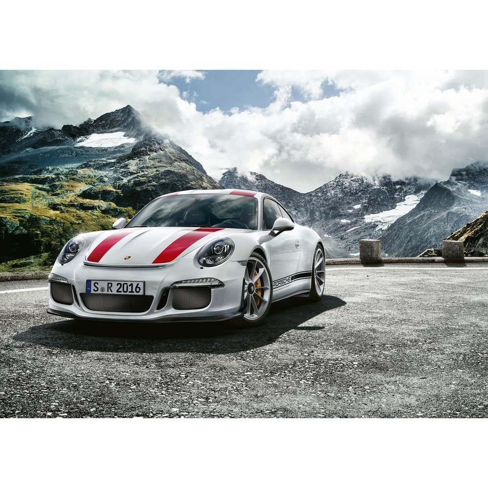 Ein weißer Porsche mit roten Streifen steht auf einer Bergstraße mit schneebedeckten Gipfeln.
