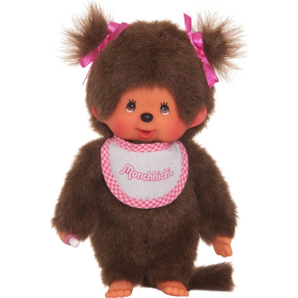 Ein brauner Monchhichi mit rosa Schleifen und Lätzchen hält einen Schnuller.