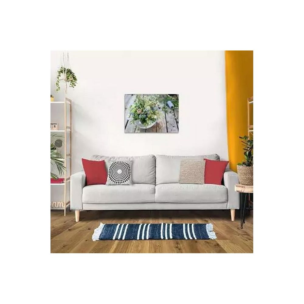 Ein hellgraues Sofa mit Kissen steht auf einem Holzboden.