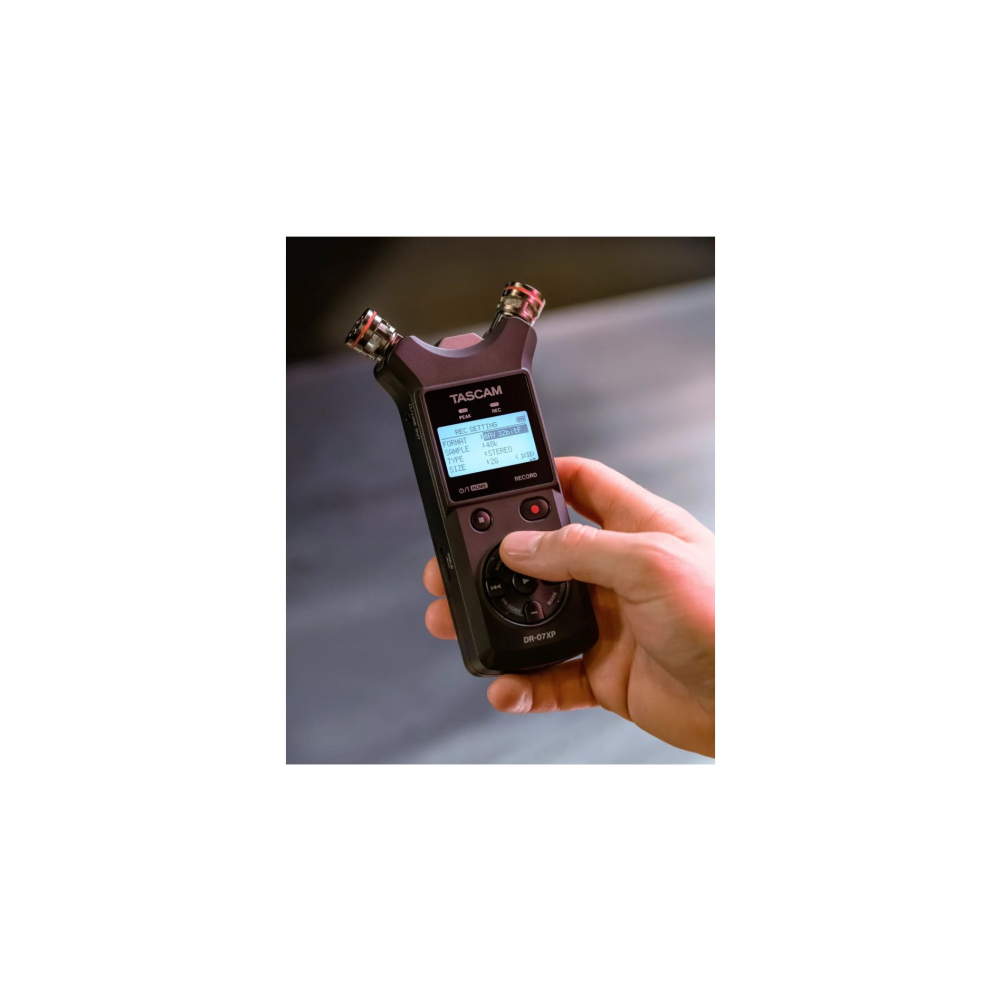 Dłoń trzyma czarny rejestrator TASCAM DR-07Xp z niebieskim ekranem.