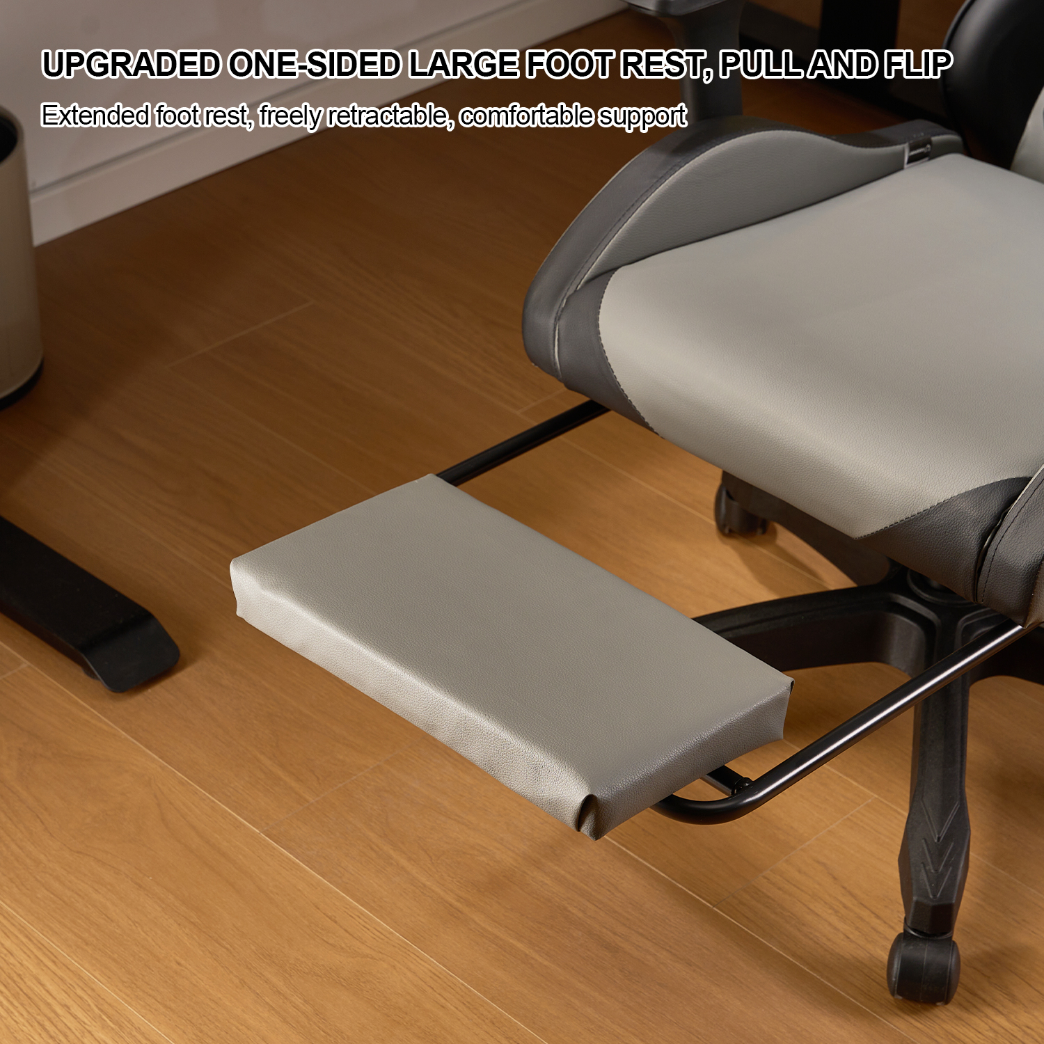 Silla gris y negra con reposapiés extendido sobre suelo de madera.