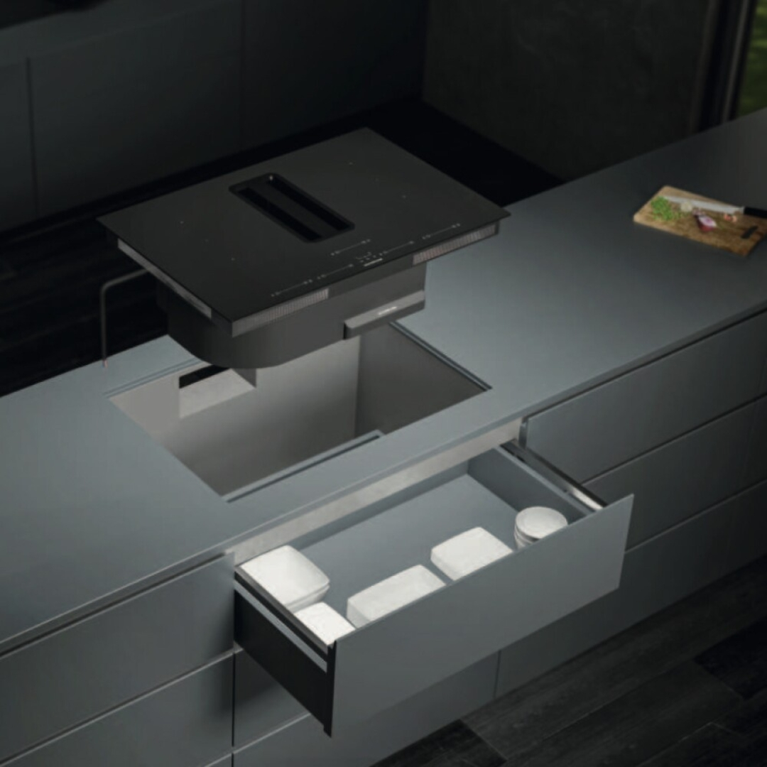 Un'isola cucina grigia moderna con cappa a scomparsa e cassetto aperto.