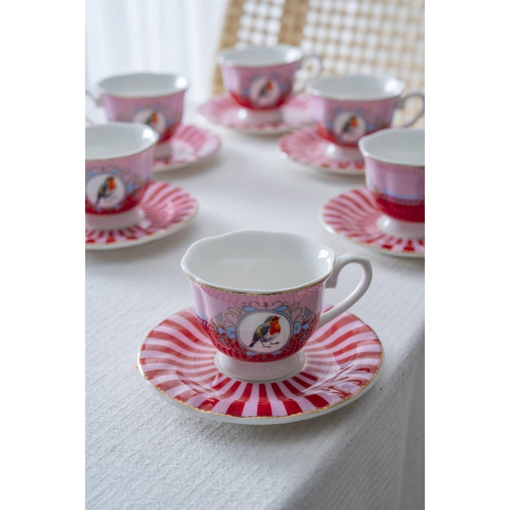 Pembe fincanlar ve tabaklar, kırmızı-beyaz çizgili ve kuş motifli.