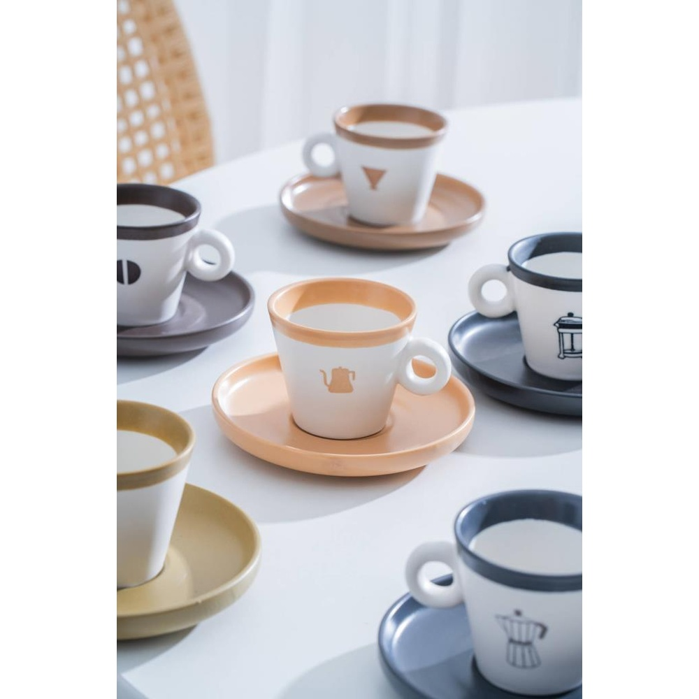 Beyaz bir masada farklı desenlerde birkaç espresso fincanı ve tabağı.