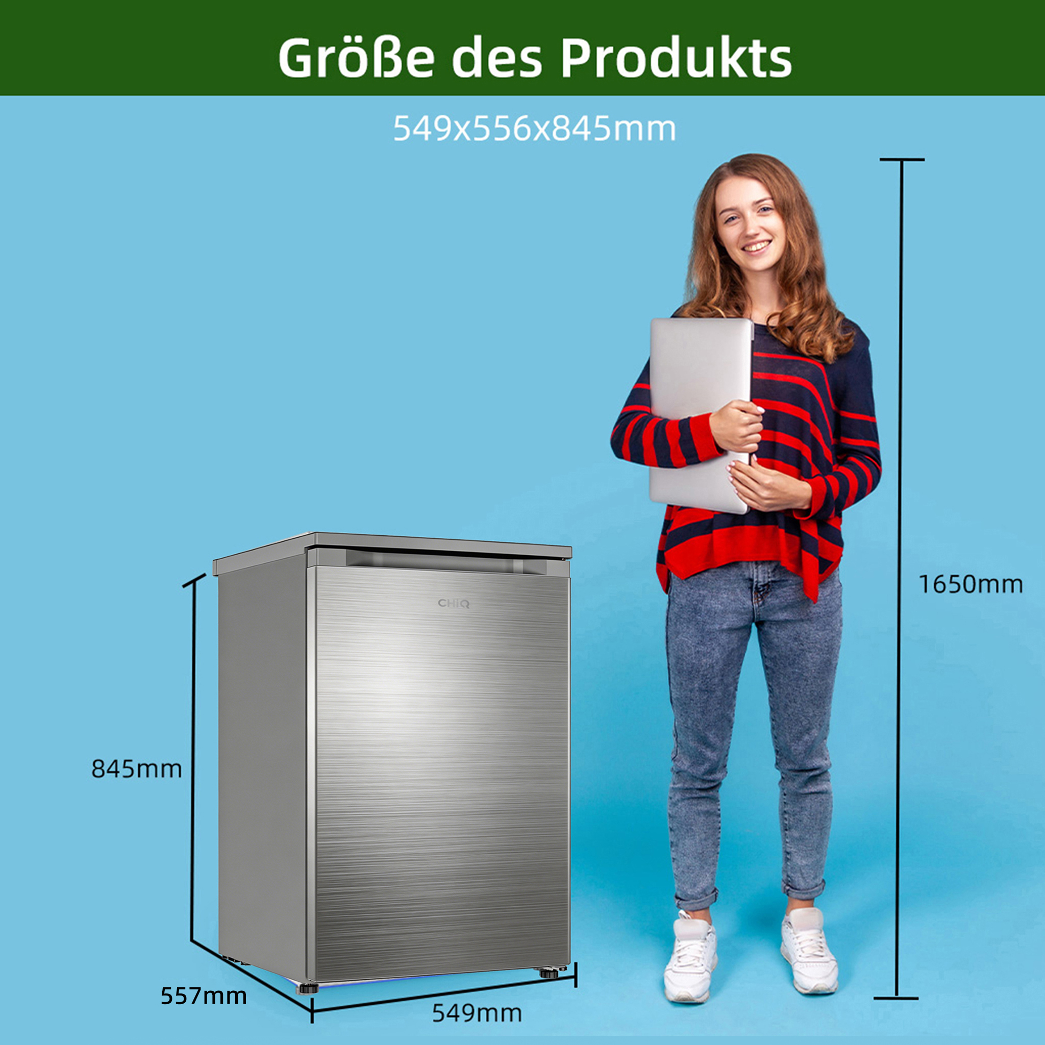 Ein junges Mädchen hält einen Laptop vor einem silbernen Kühlschrank.