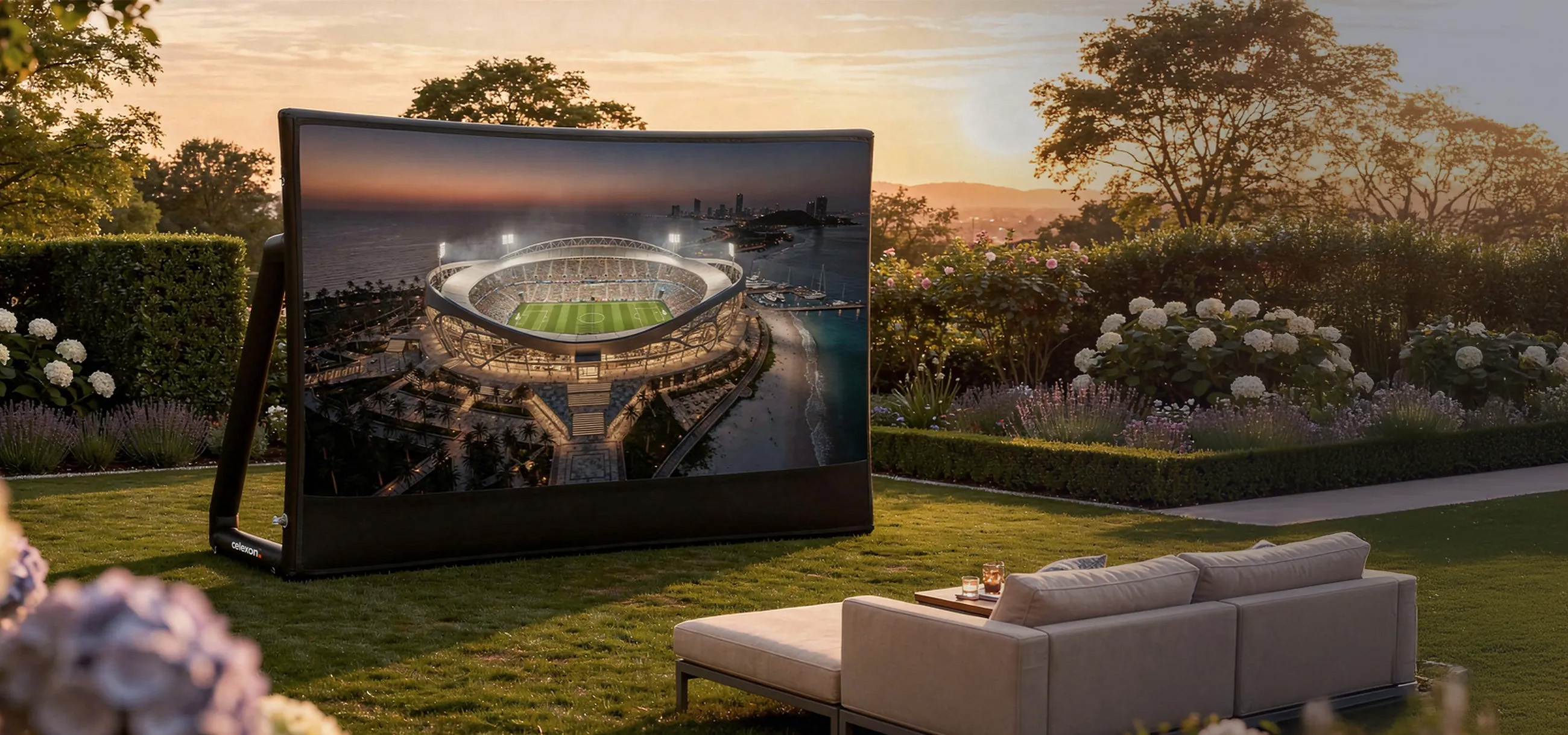 Ein aufblasbarer Bildschirm zeigt ein Stadion am Meer bei Sonnenuntergang.