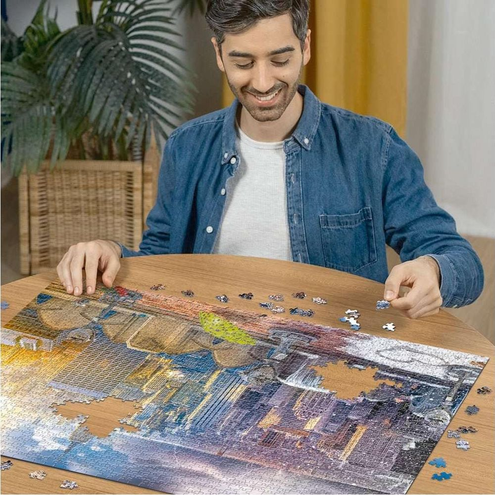 Un homme complète un puzzle de paysage urbain nocturne avec de nombreuses lumières.