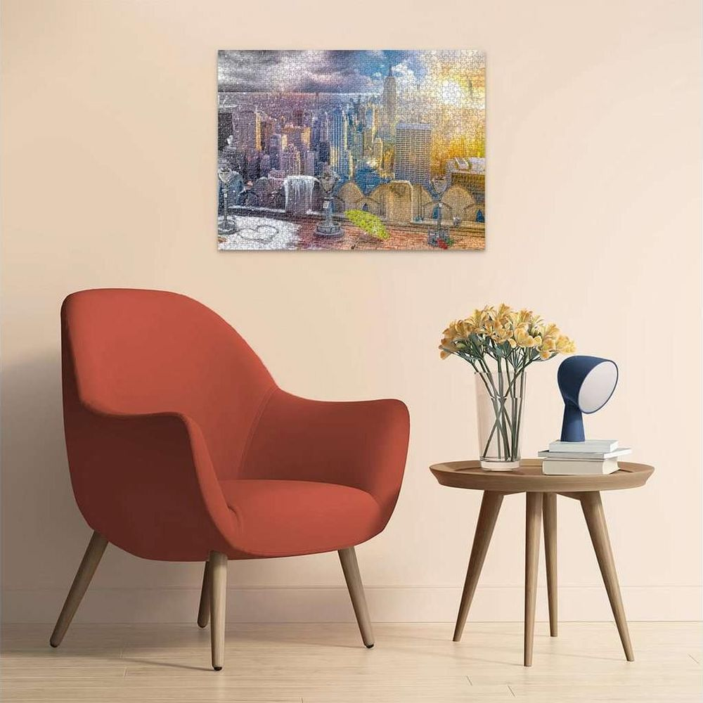Un puzzle de paysage urbain au coucher du soleil est accroché au-dessus d'une chaise rouge.