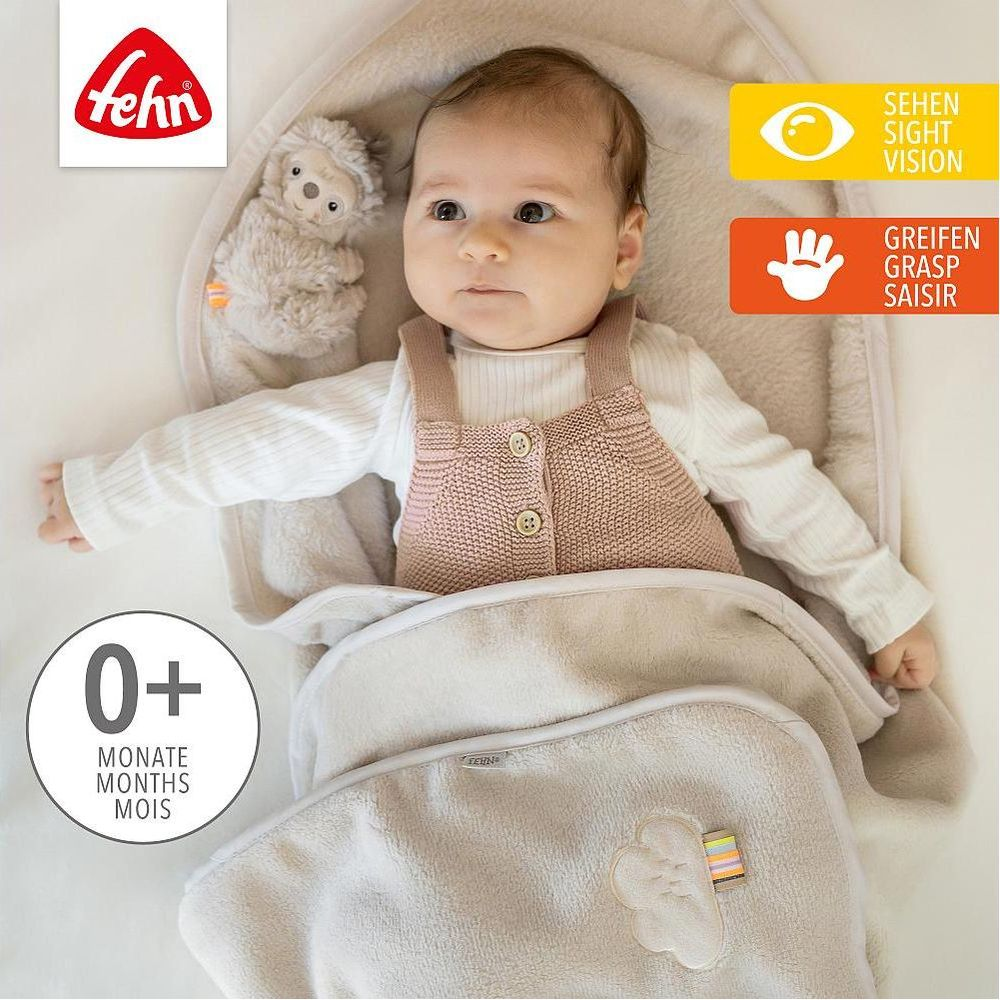 Baby in Decke, Spielzeug, "0+" und Produktinfos. Fehn Logo.