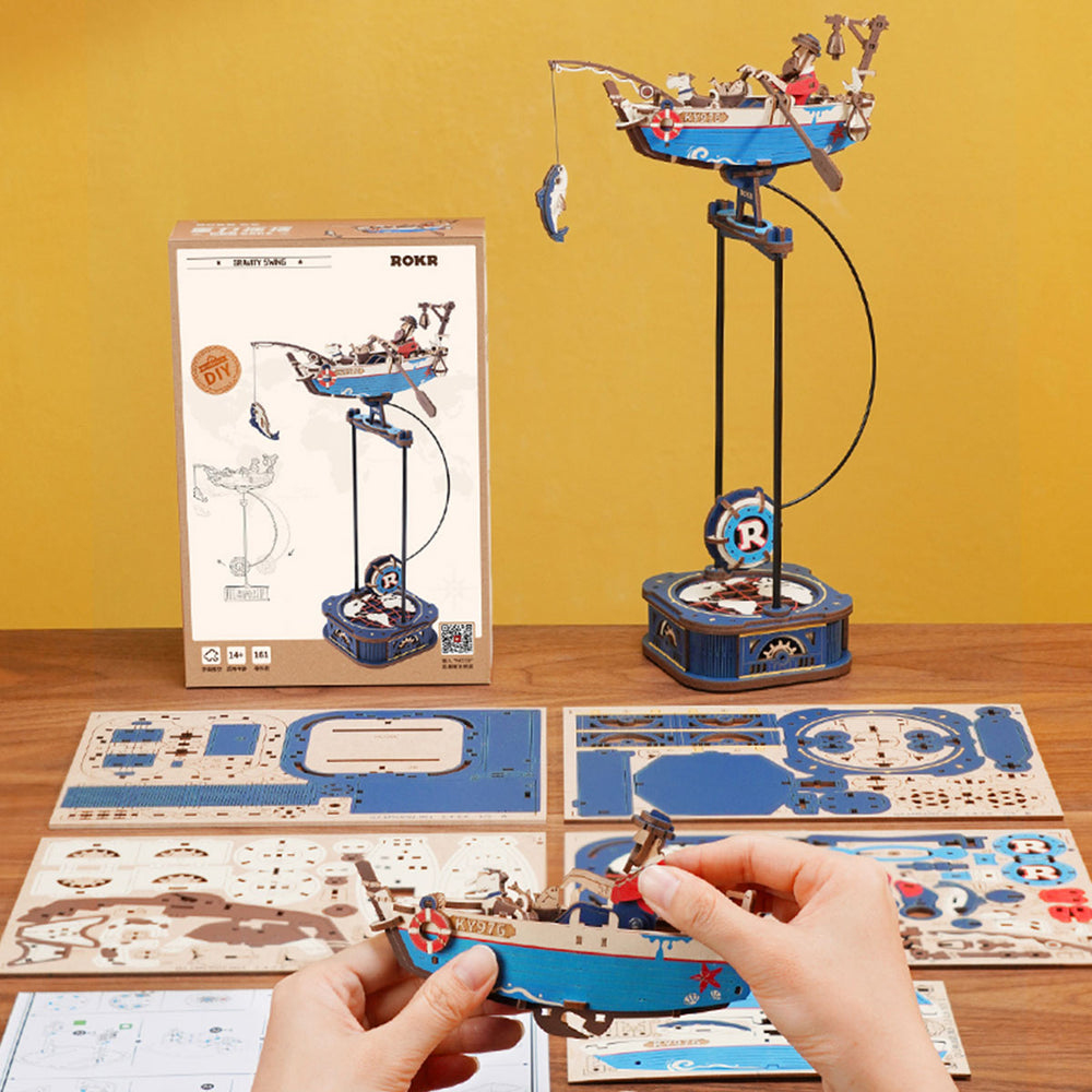 Maquette de bateau de pêche lançant une ligne, avec emballage et plans à côté.